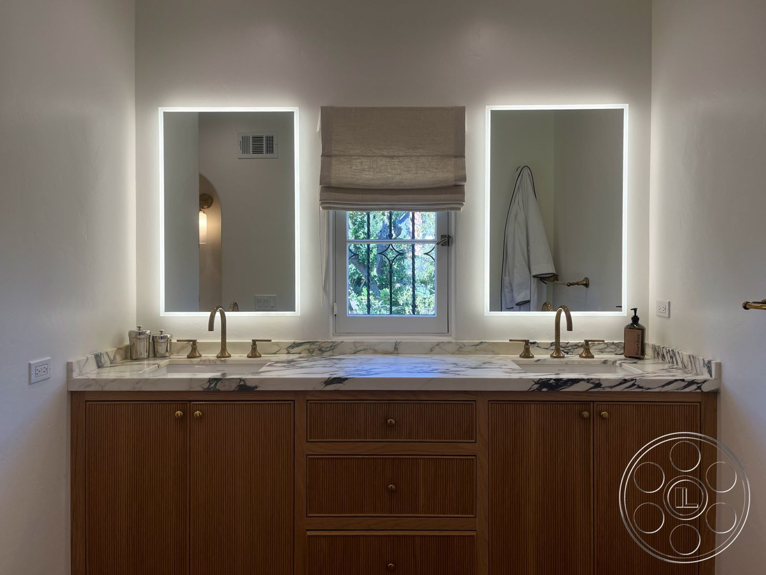 Medit 166 - textured plaster walls, minimalist bathroom decor, interior bathroom with marble countertop, brass faucet fixtures, wood cabinetry with horizontal paneling, backlit mirror with modern design, luxury bathroom lighting, window with iron grille, soft fabric window treatment, modern washstand design