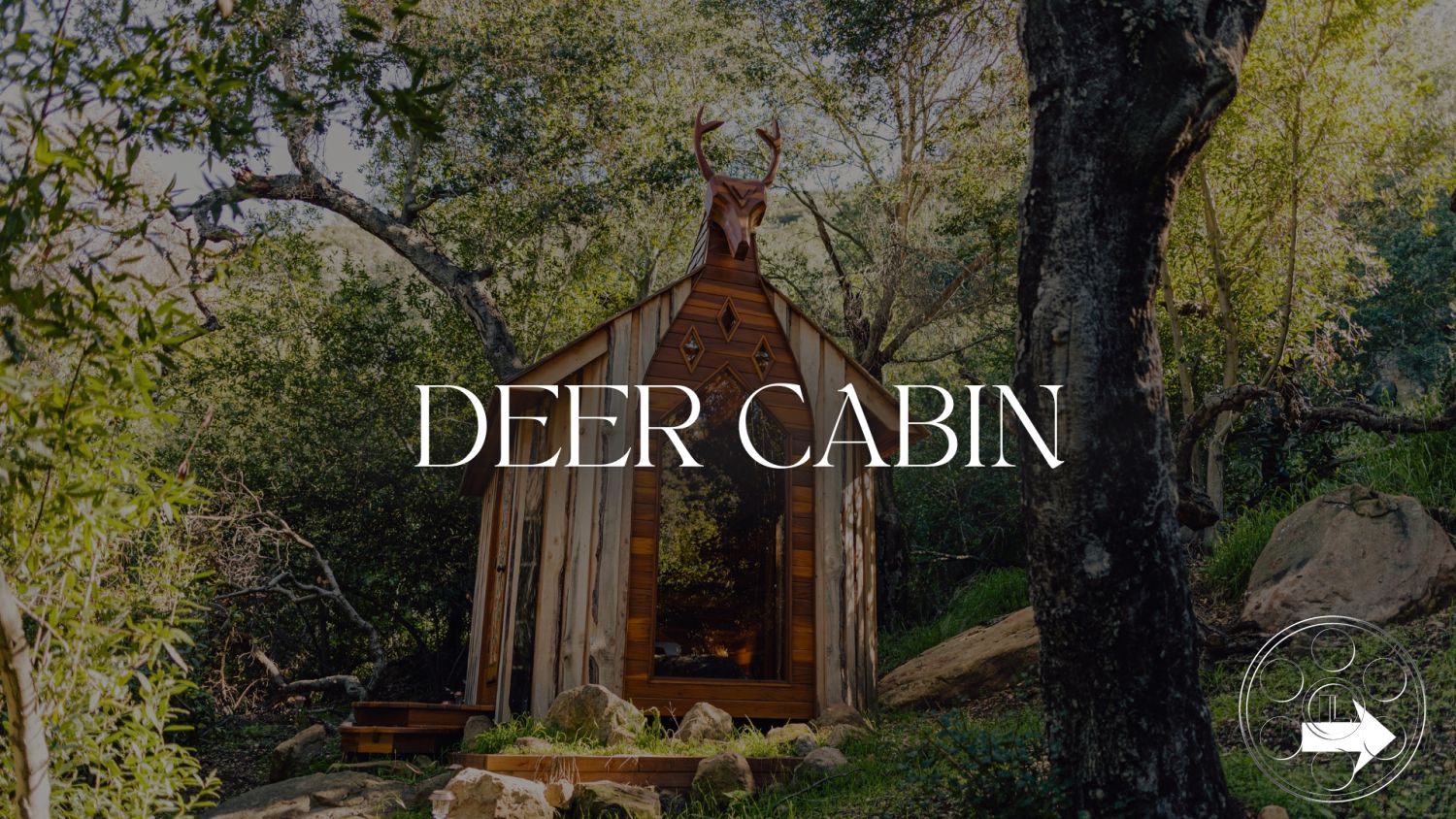 Topanga Retreat - minimalist decor, rustic architecture, wood siding, surrounded by trees, gabled roof shape, natural light interior, glass door entrance, scenic countryside view, forest setting, natural stone landscaping, integrated with nature, open-air relaxation space, wood cabin exterior, sloped roof with deer statue, small cabin design