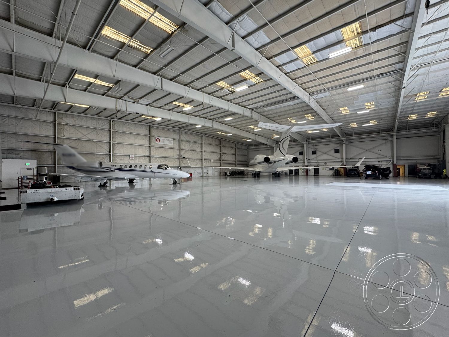 VN Hangar - open floor plan, industrial lighting fixtures, safety signage, industrial environment, maintenance area, concrete foundation, steel frame construction, high ceiling design, utility access points, metal roof panels, exterior hangar structure, polished epoxy flooring, large unobstructed space, commercial aircraft hangar, exposed truss framework, fire suppression system, aircraft parking area, hangar door openings, clear span architecture, insulated wall panels, aircraft storage space, tarmac access, hangar equipment storage, large overhead doors, city airport proximity