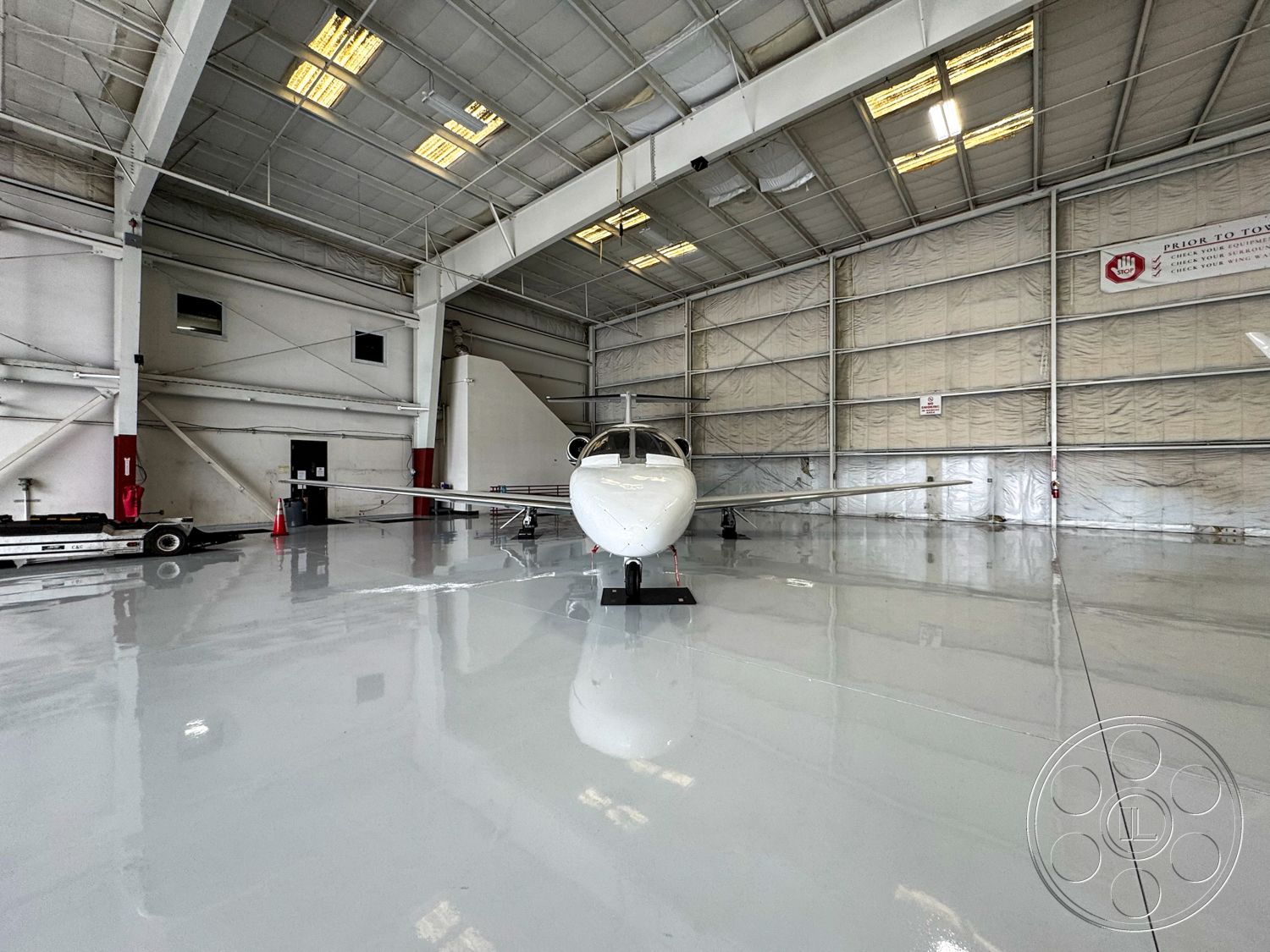 VN Hangar - industrial lighting fixtures, ventilation system, steel frame construction, open interior space, utility room, painted concrete floor, exterior hangar structure, clear span architecture, large overhead doors, insulated metal panel walls, high-gloss epoxy floor, raised ceiling, fire safety equipment, aircraft storage area, sliding hangar door system, hangar with skylights, aircraft maintenance space