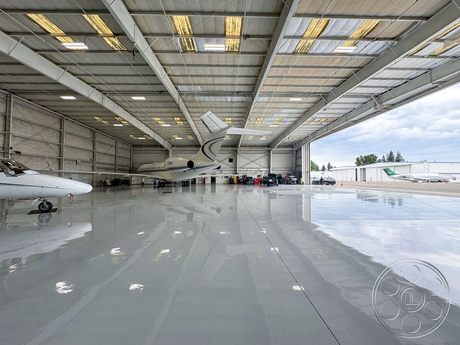 VN Hangar - workshop area, open space layout, industrial lighting fixtures, ventilation system, smooth concrete walls, aircraft maintenance area, large hangar doors, modern aviation facility, interior airplane hangar, epoxy-coated concrete floor, high ceiling with exposed metal beams, wall-mounted storage units, reinforced steel structure, drive-up access for vehicles, spacious aircraft parking, wireless charging stations, painted safety markings on floor, windowed walls for natural light, maintenance tool wall, multi-purpose hangar space