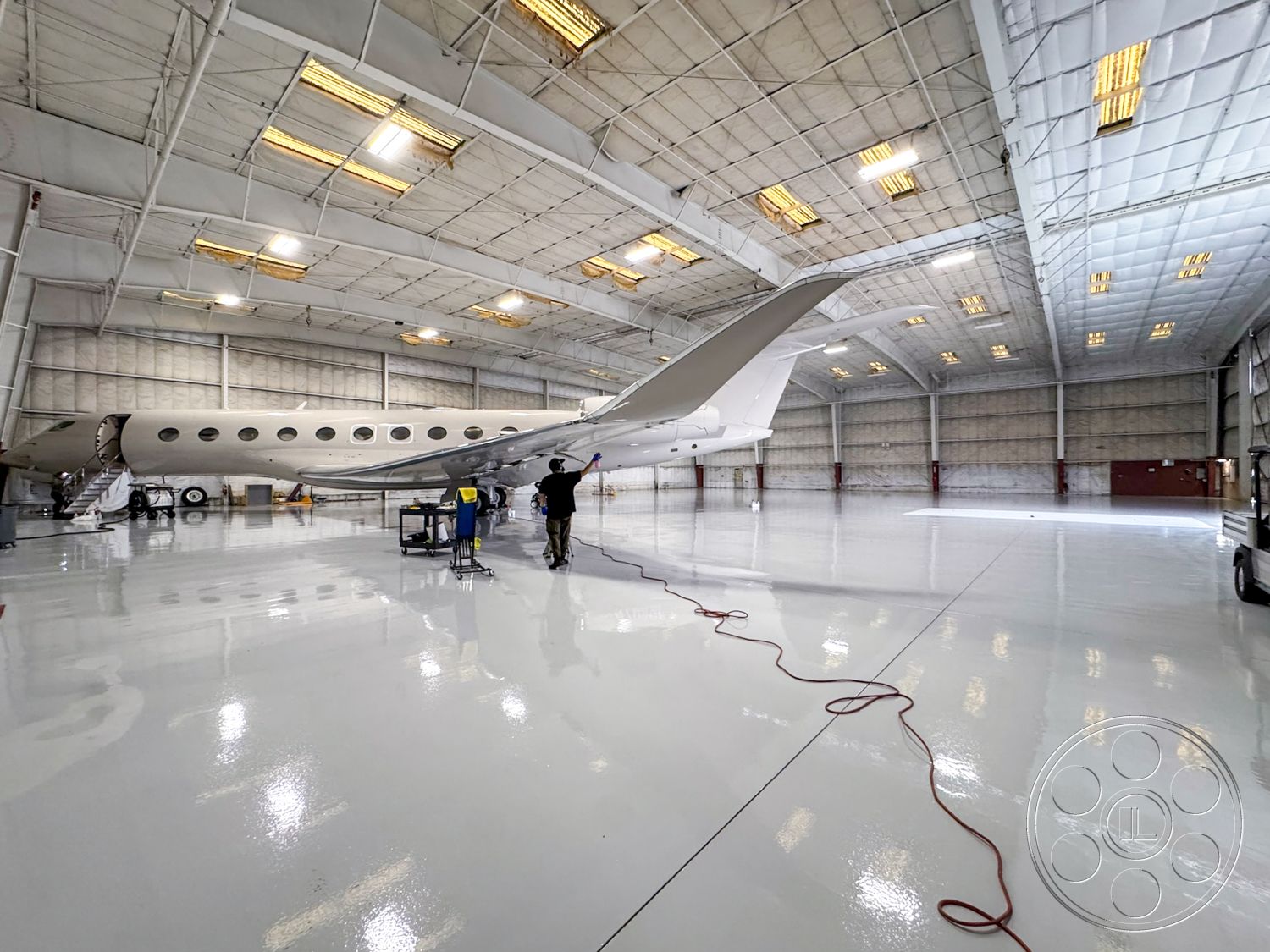 VN Hangar - polished concrete floor, industrial space, aircraft hangar interior, epoxy flooring, high ceiling structure, metal arch beams, hangar lighting fixtures, vinyl wall coverings, machinery servicing area, large sliding hangar doors