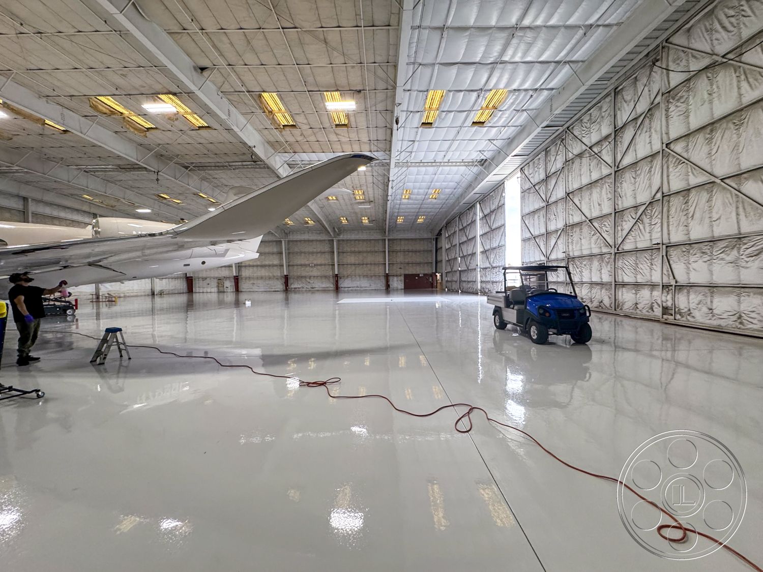 VN Hangar - open floor plan, large glass windows, bright fluorescent lighting, concrete slab foundation, flexible workspace design, spacious interior layout, painted drywall, aircraft maintenance area, commercial hangar interior, epoxy-coated hangar floor, industrial high ceilings, metal support beams, insulated fabric walls, aeronautics workspace, steel overhead doors, fire-resistant wall materials, rounded hangar shape, utility golf cart parking, high-performance insulation, aircraft servicing area