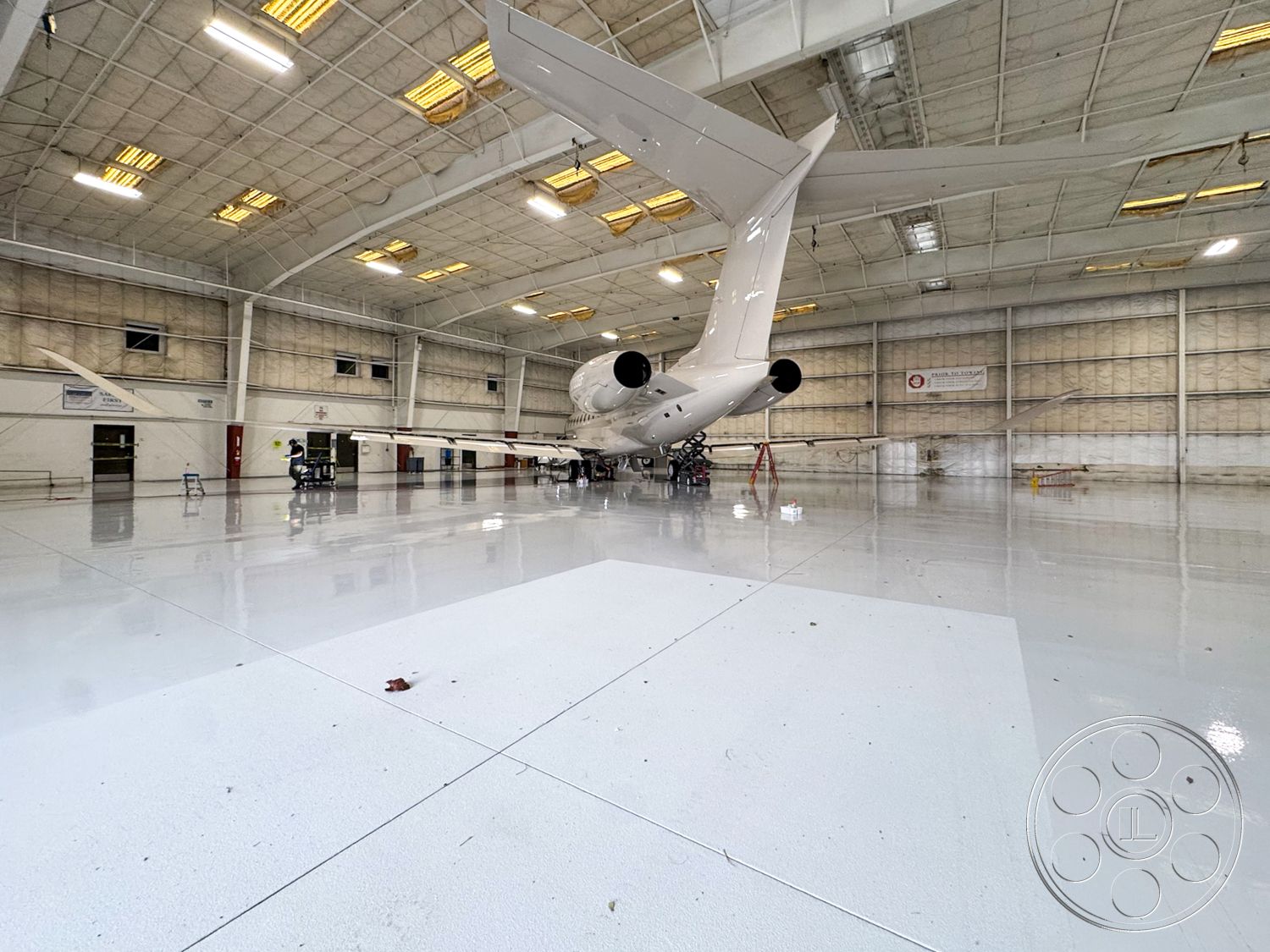 VN Hangar - open floor plan, functional workspace, industrial design elements, safety signage, concrete foundation, aircraft maintenance area, aircraft storage area, interior hangar space, epoxy resin flooring, high ceiling aviation facility, exposed metal beam structure, white insulated wall panels, large overhead lighting fixtures, clear span hangar, fire safety features, maintenance tool storage, efficient workflow layout, cleanroom-like environment, aircraft access door