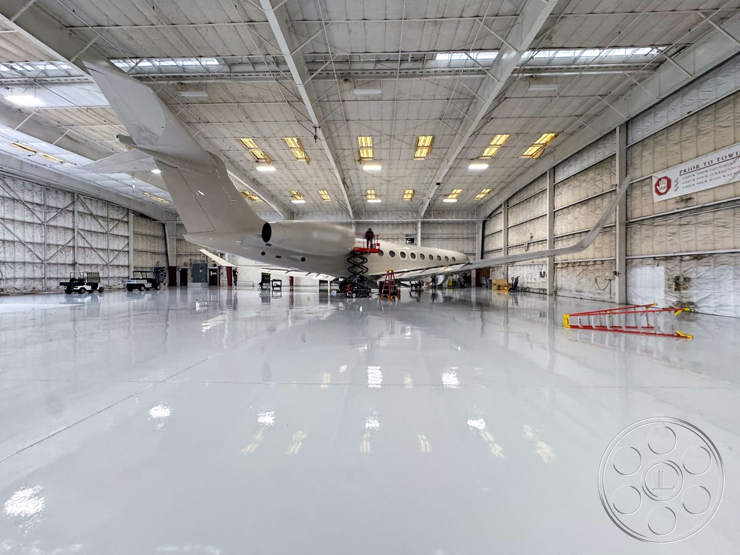 VN Hangar - polished concrete floor, industrial lighting fixtures, spacious open layout, drywall interior walls, large bay windows, metal frame structure, exterior steel aircraft hangar, high ceiling warehouse space, acoustic insulation panels, hangar door with large openings, reinforced steel trusses, reflective epoxy floor coating, clear span construction, flying bridge service area, workshop space for aircraft maintenance, exterior parking area for service vehicles, flight service area, aircraft maintenance zone, ventilation system for exhaust, safety signage and barriers