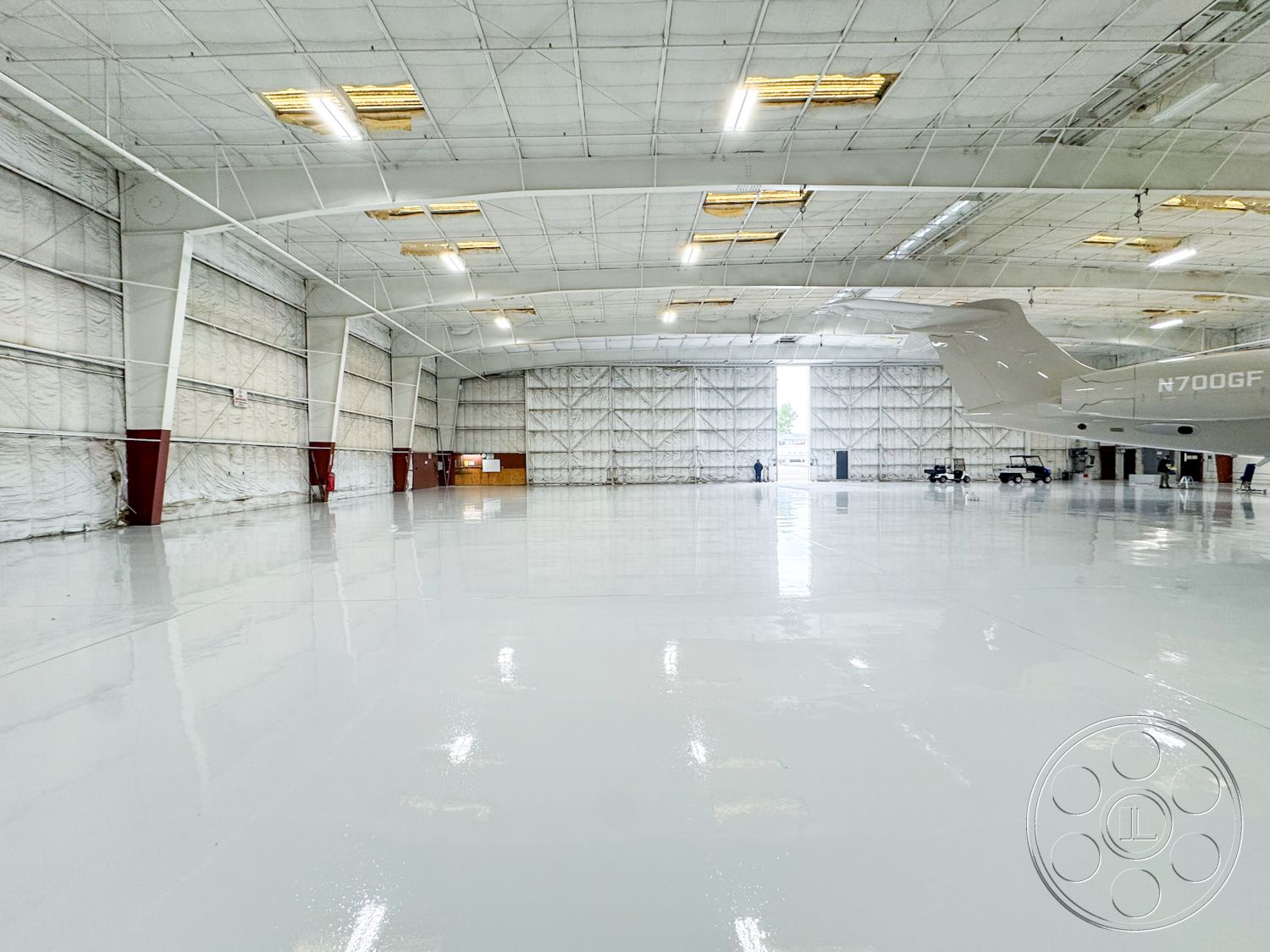 VN Hangar - large open space, ventilation ducts, modern industrial design, industrial storage space, insulated wall panels, high ceilings with exposed trusses, exterior aircraft hangar, metal frame construction, white painted steel walls, glass hangar doors, concrete floor coating, reflective epoxy floor, flush lighting fixtures, weatherproof wall coverings, airport hangar setting, clean modern aesthetic
