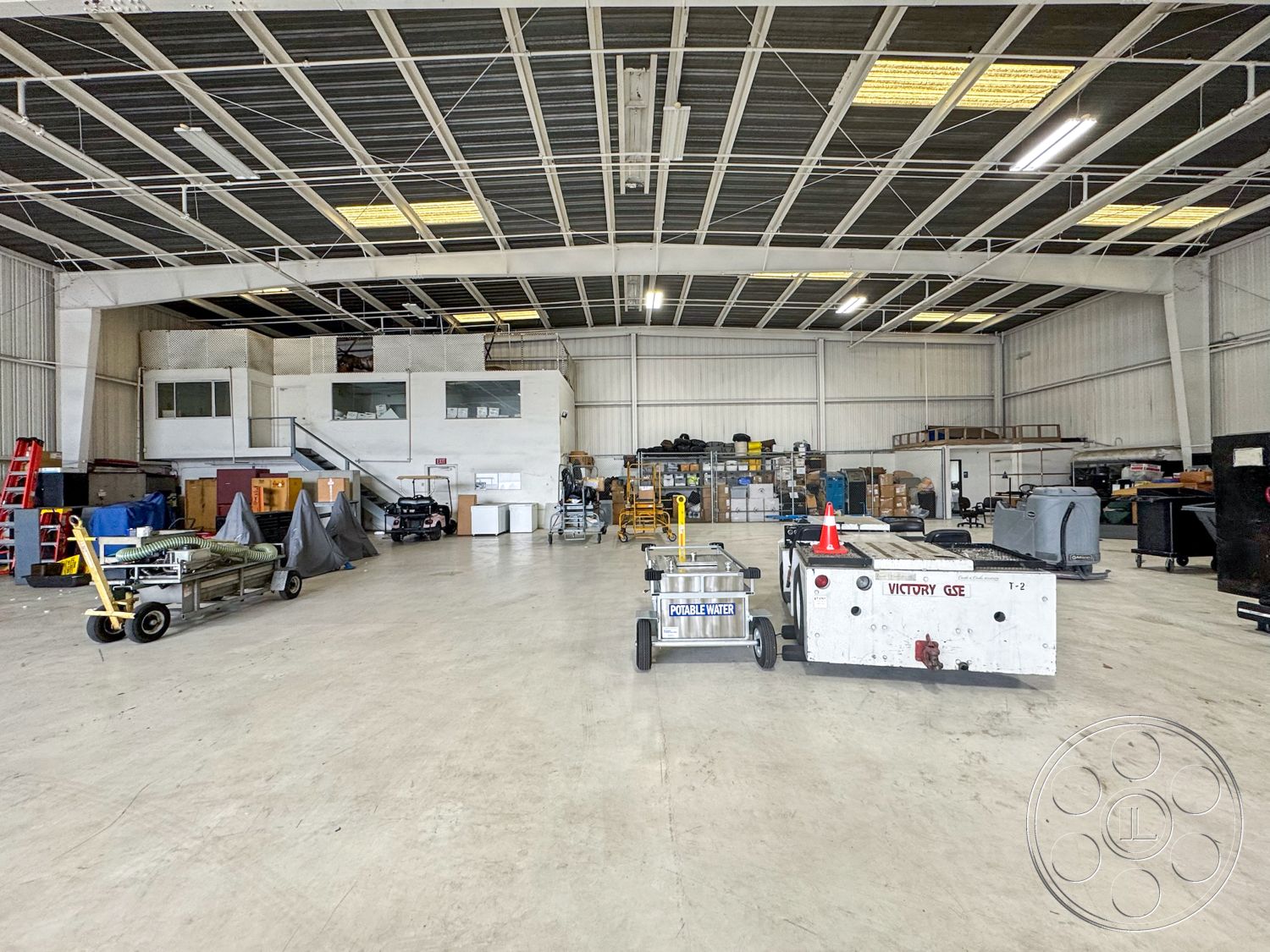 VN Hangar - open floor plan, large windows for natural light, exposed ductwork, concrete floor slab, functional utility space, metal frame construction, interior industrial space, steel roof trusses, high ceiling warehouse, lofted office area, roller door access, storage shelving units, painted drywall partitions, commercial storage environment