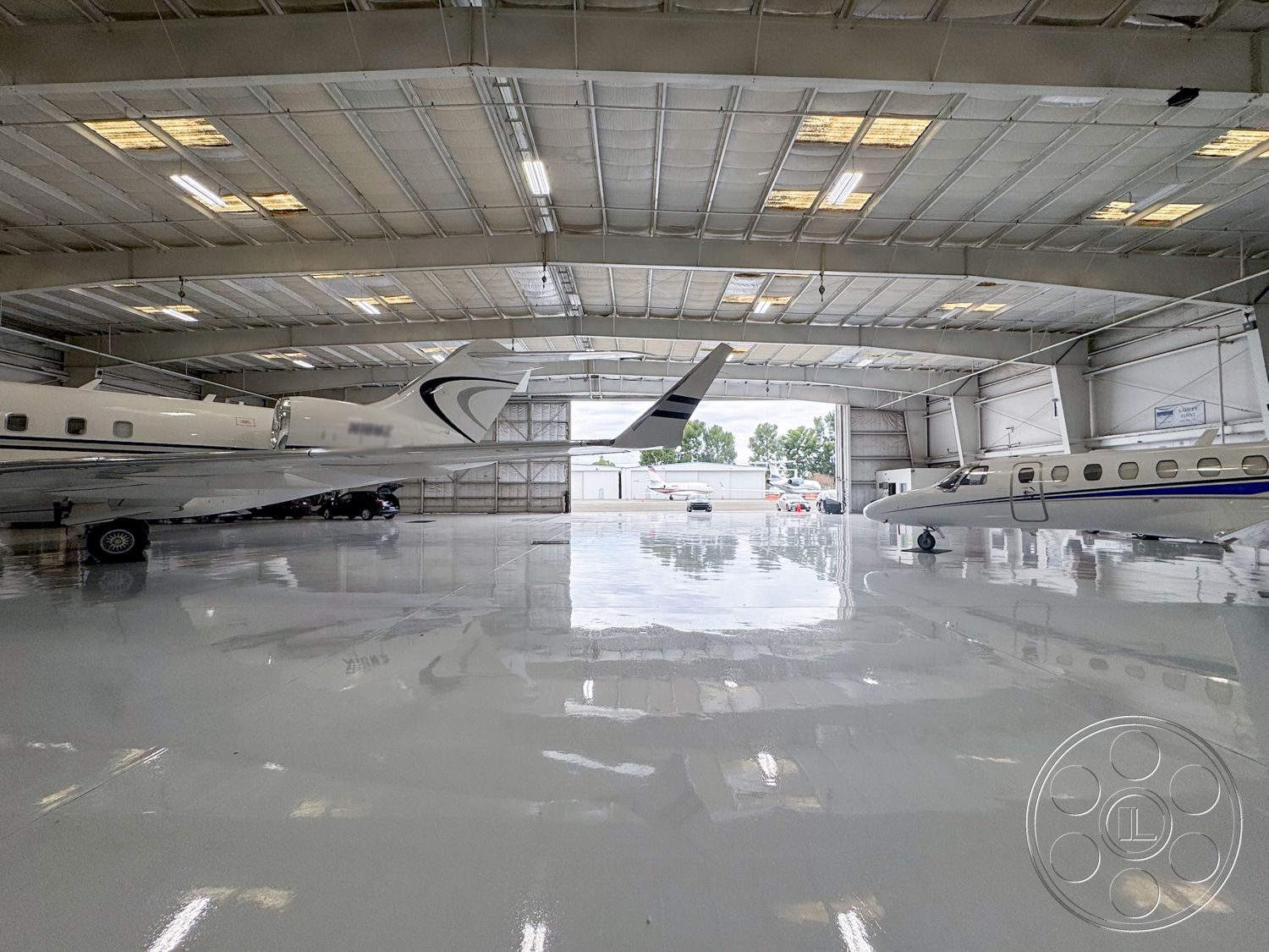 VN Hangar - commercial lighting fixtures, aircraft maintenance area, aircraft storage area, exterior aircraft hangar, metal siding hangar walls, smooth epoxy flooring, industrial ceiling with skylights, large garage door openings, high ceilings for aircraft clearance, open space for maneuvering, concrete exterior foundation, insulated steel roof, customized hangar design, airport ground view, modern hangar architecture, efficient aircraft shelter