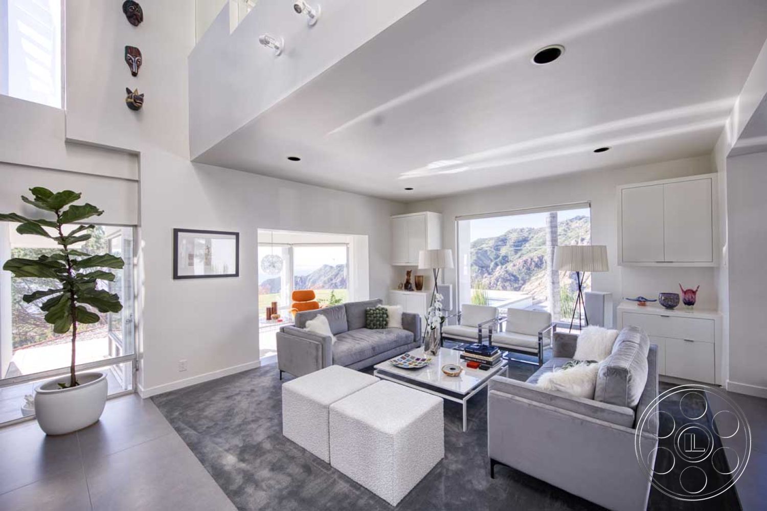 Modern 56 - minimalist decor, soft neutral color palette, contemporary furniture, open floor plan, floor-to-ceiling windows, textured throw pillows, accent lighting, metal and glass coffee table, white painted walls, light gray carpet flooring, modern living room, built-in white cabinetry, large mountain view, potted decorative plant, sculptural wall art, natural light-infused space