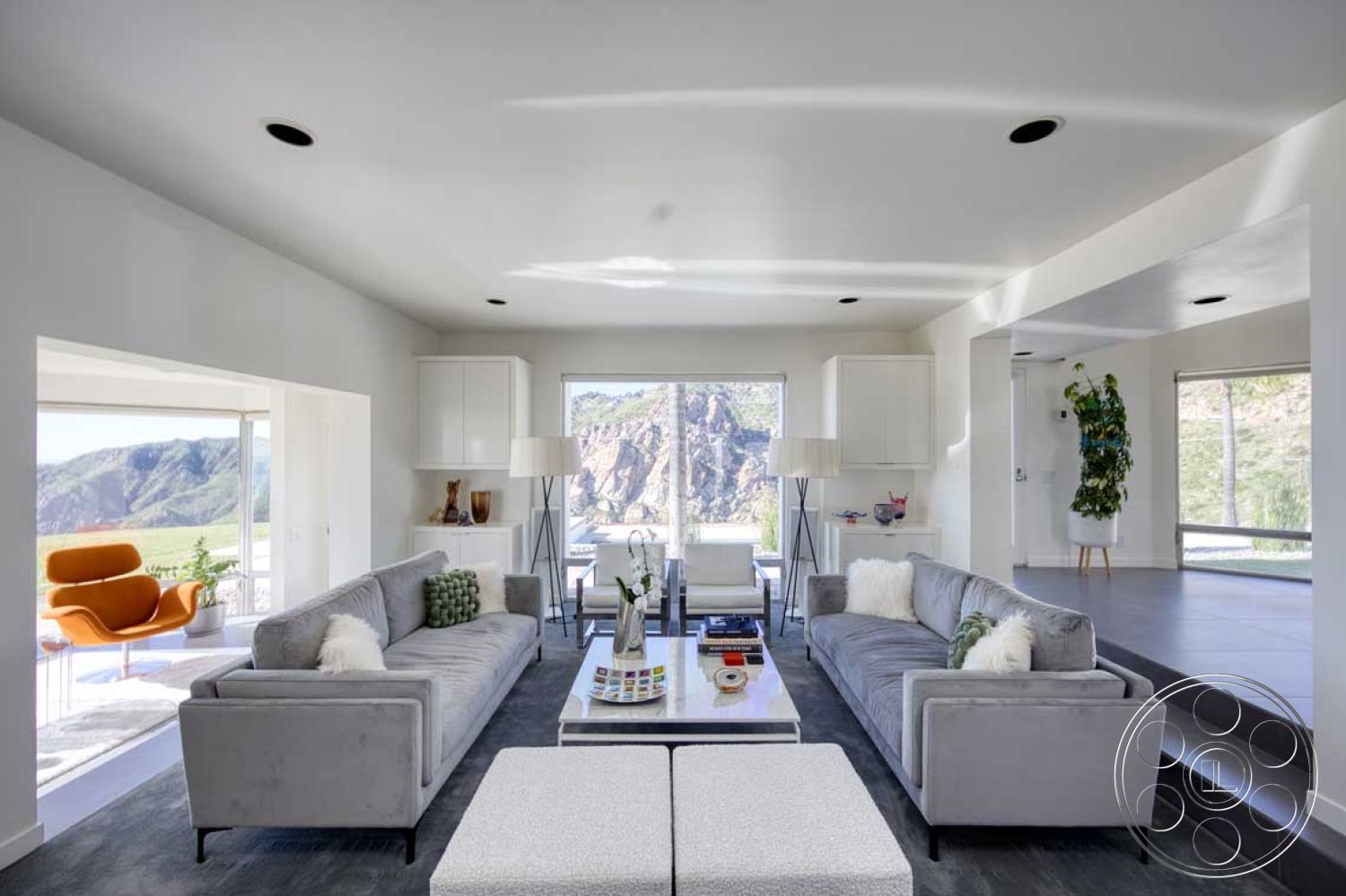 Modern 56 - stylish floor lamp, floor-to-ceiling windows, elegant light fixtures, soft natural light, geometric decor elements, open-concept layout, multicolored throw pillows, mountain view setting, sliding glass door access, potted greenery accents, modern glass coffee table, minimalist white walls, interior contemporary living room, light gray upholstered sofas, textured gray carpet flooring, cabinets with clean lines, modern accent chair, decorative coffee table books