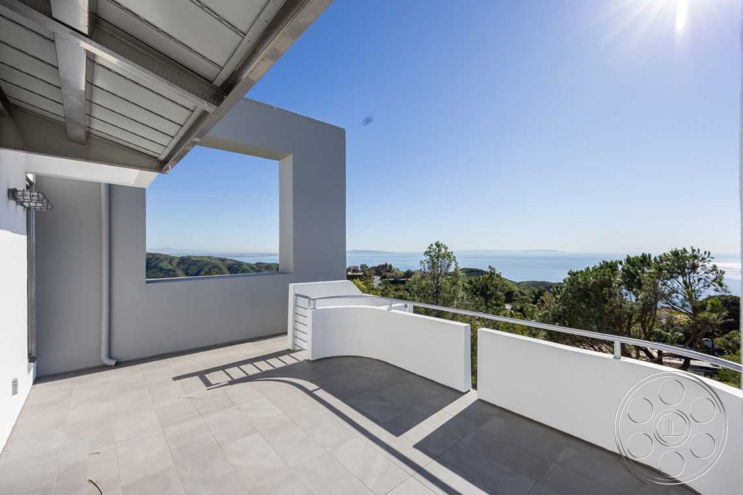 Modern 56 - exterior, white stucco walls, clean lines, minimalist design elements, metal railing, floor-to-ceiling windows, modern architectural style, large sliding glass doors, flat roof design, concrete patio flooring, smooth surface finishes, surrounding hillside landscape, expansive ocean view, open balcony space