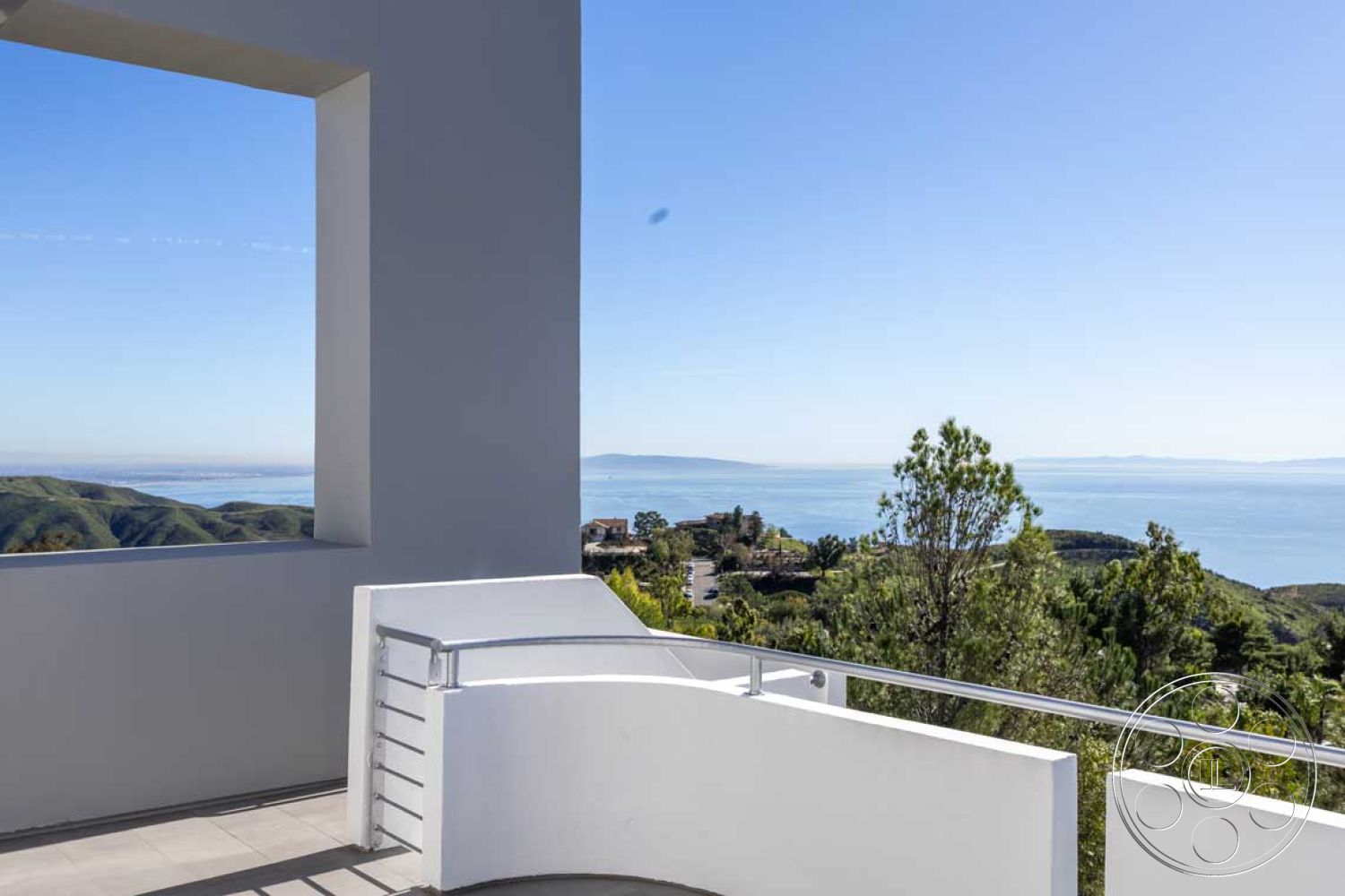 Modern 56 - white stucco walls, modern architectural style, mountain view setting, oceanfront property, exterior glass balcony railings, natural landscape backdrop, interior concrete patio floor, rectangle window frame, curved balcony shape, open-air terrace design