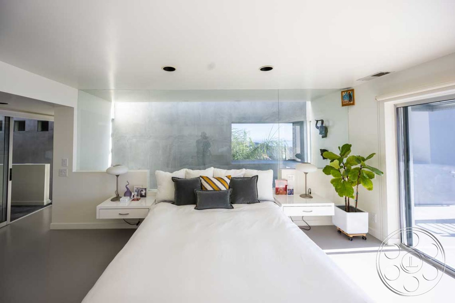 Modern 56 - neutral color palette, hardwood flooring, open concept layout, seamless indoor-outdoor transition, soft white bedding, decorative throw pillows, modern minimalist style, minimalist interior design, clean lines and geometric forms, luxury master bedroom, indoor plant accent, natural light from sliding glass doors, glass wall panels, modern bedroom furniture, floating nightstands, concrete bedroom walls