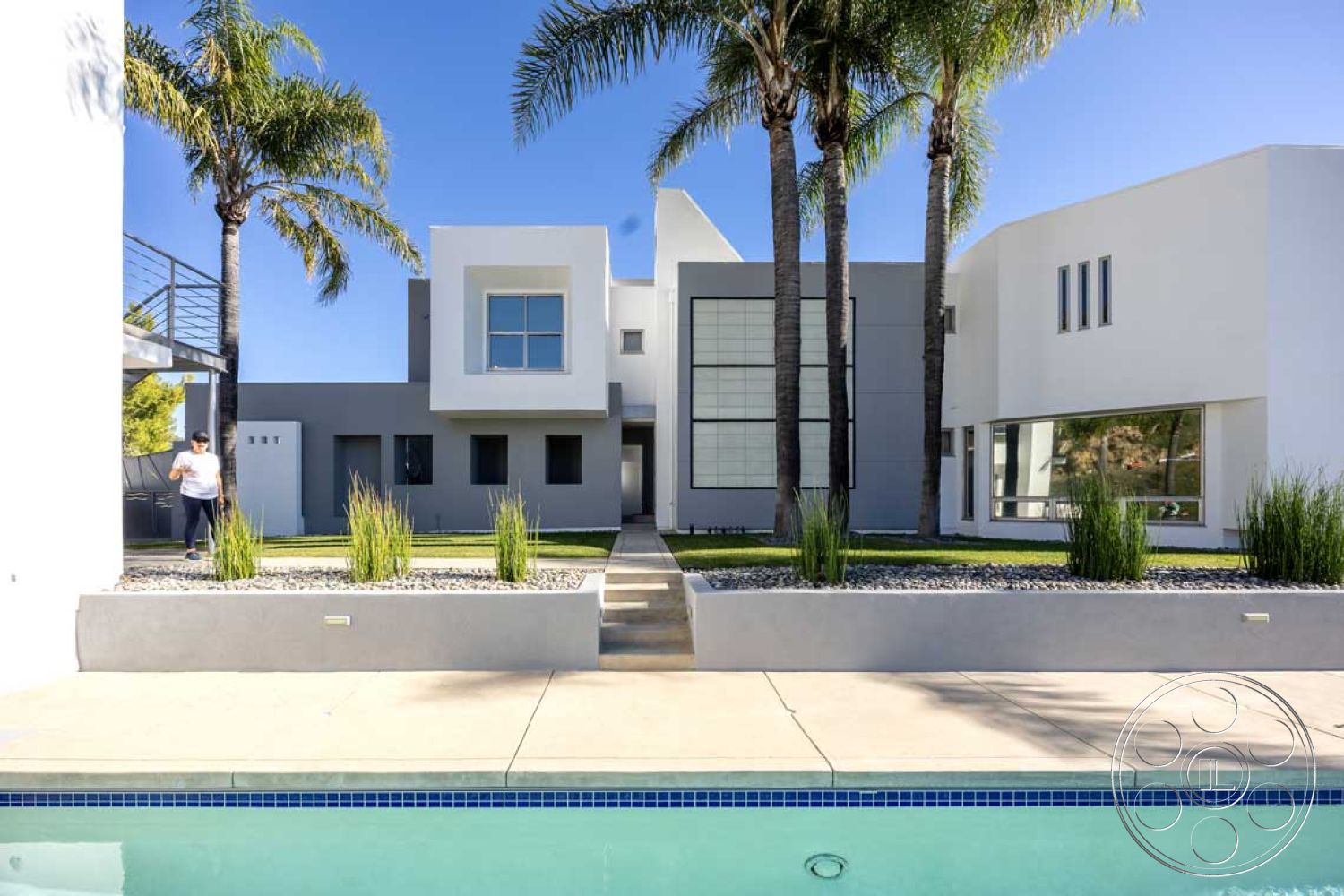 Modern 56 - white stucco walls, rectangular swimming pool, outdoor living space, large floor-to-ceiling windows, urban residential setting, gray concrete pathway, smooth concrete pool deck, flat roof design, landscaped garden area, minimalist architectural style, modern geometric architecture, metal balcony railing, exterior contemporary home, palm trees in yard, crushed stone landscape