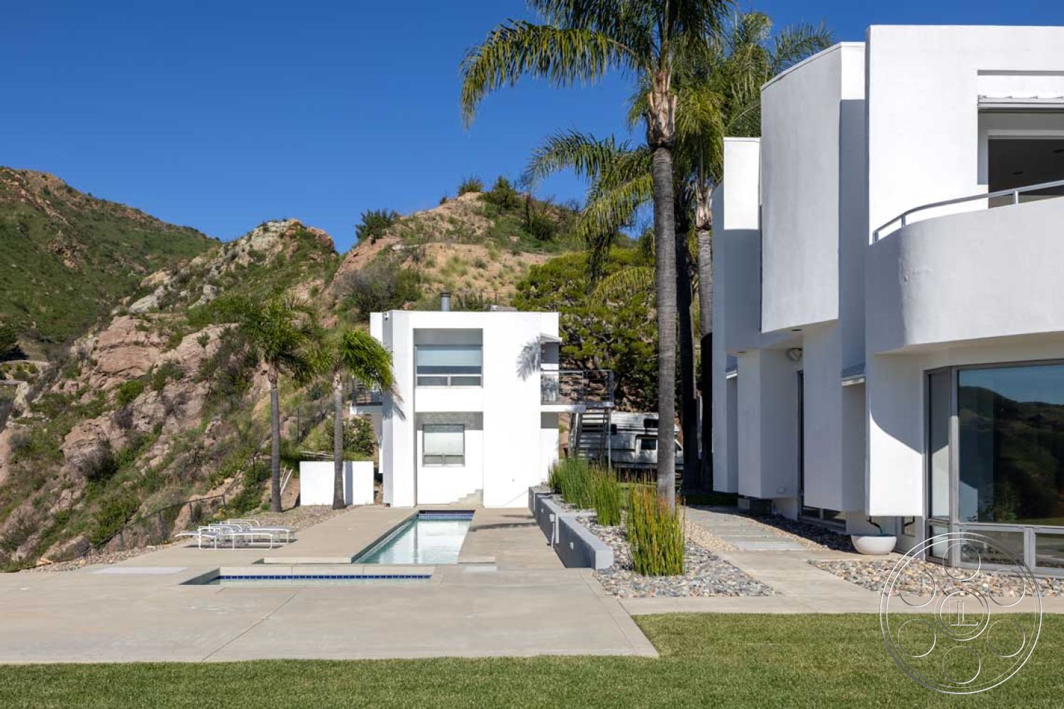 Modern 56 - glass sliding doors, metal railings, rectangular swimming pool, floor-to-ceiling windows, modern architectural style, open outdoor space, sunny outdoor area, minimalist landscaping, mountain view setting, interior open floor plan, exterior white stucco walls, concrete patio floor, exposed aggregate concrete walkway, lush landscape with palm trees, curved building elements, interior modern design