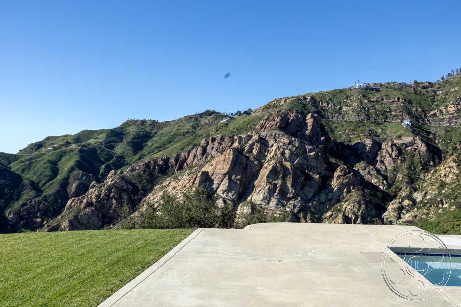 Modern 56 - contemporary design, modern architecture, rectangular swimming pool, lush green lawn, mountain view, outdoor relaxation space, open-air setting, concrete patio floor, sunny hillside location, exterior landscape, flat pool deck, minimalist outdoor living area, surrounded by natural rock formations