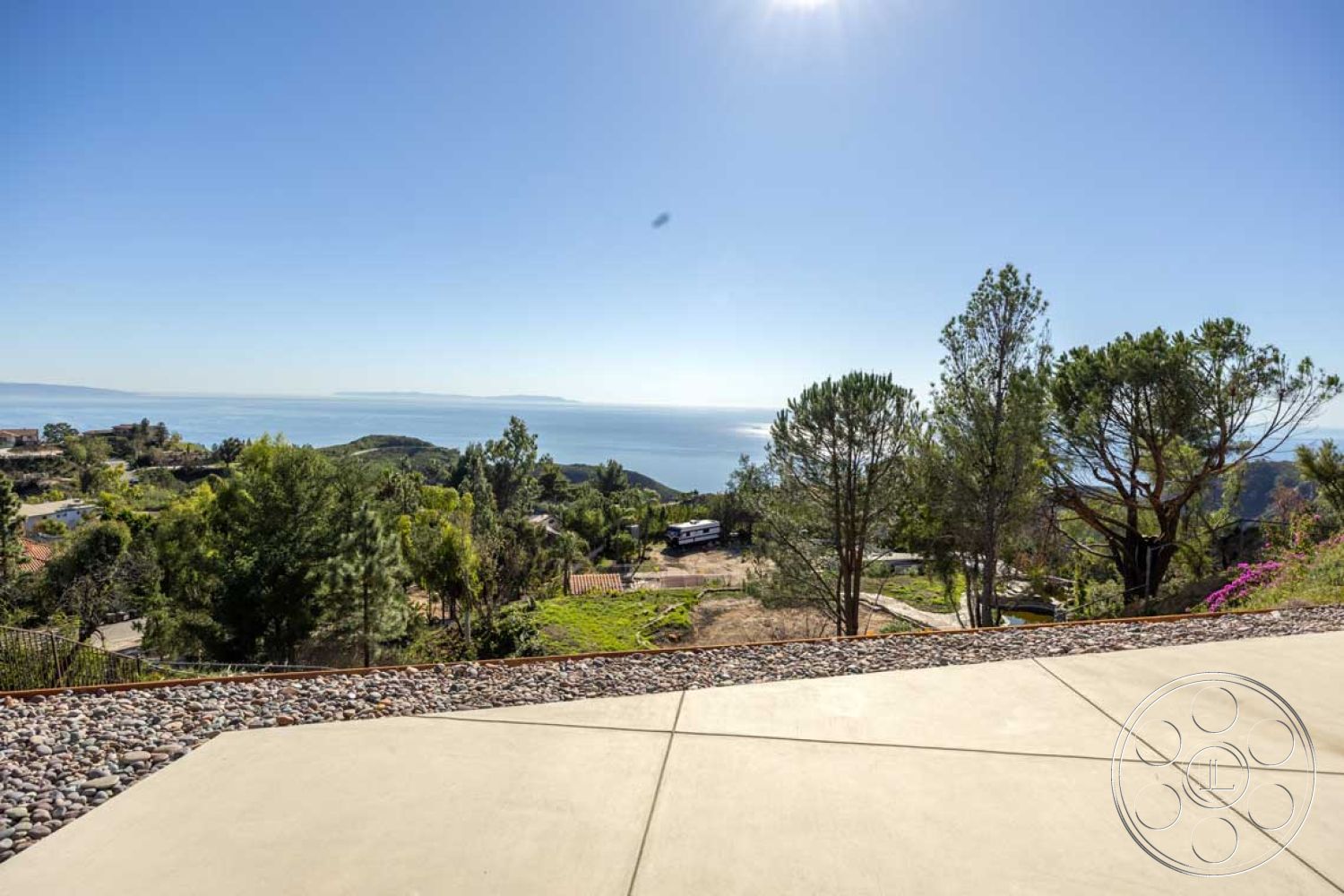 Modern 56 - sloped terrain, hillside location, lush greenery backdrop, mountain view setting, oceanfront property, exterior concrete patio flooring, landscape stone border, bushy trees, modern outdoor entertaining area