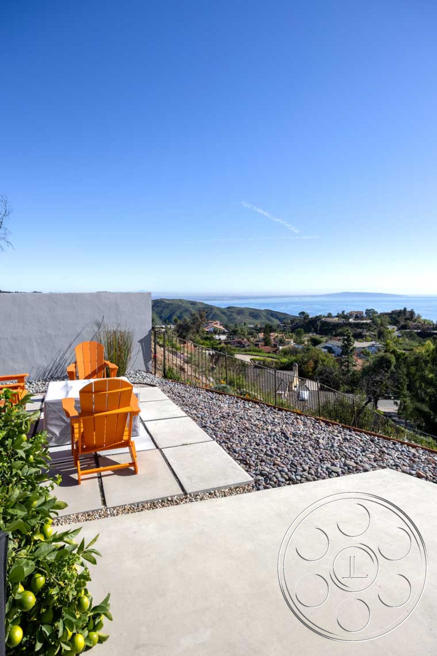 Modern 56 - exterior, metal railing, clear blue sky, succulent garden, hillside location, minimalist outdoor space, mountain view setting, modern outdoor seating area, concrete patio floor, stone gravel landscaping, orange Adirondack chairs, flat landscape design