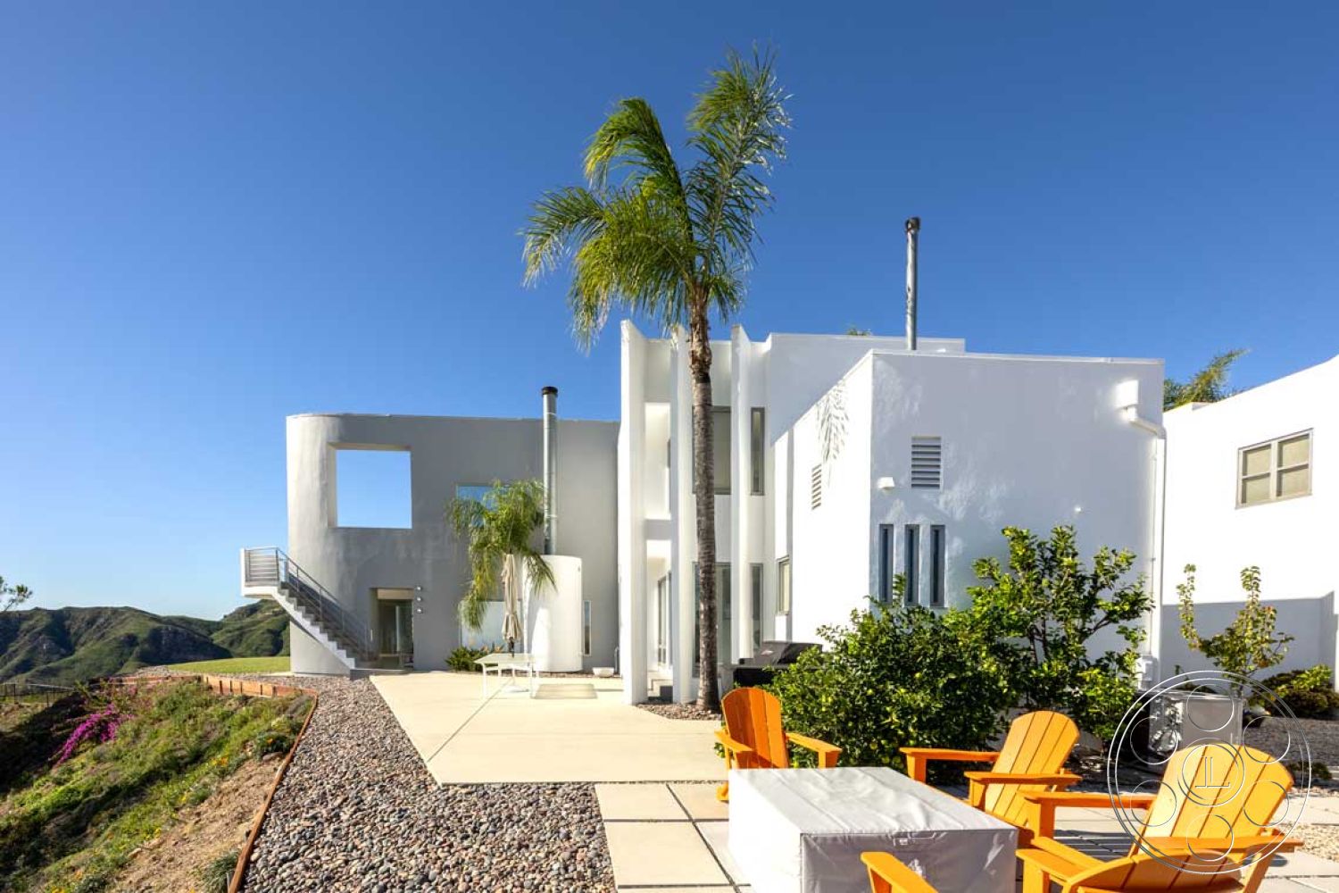 Modern 56 - exterior, white stucco walls, minimalist design elements, contemporary architecture, gravel landscaping, hillside location, rectangular windows, smooth concrete patio, flat roof design, modern outdoor seating area, steel stair railings, palm trees in landscaping
