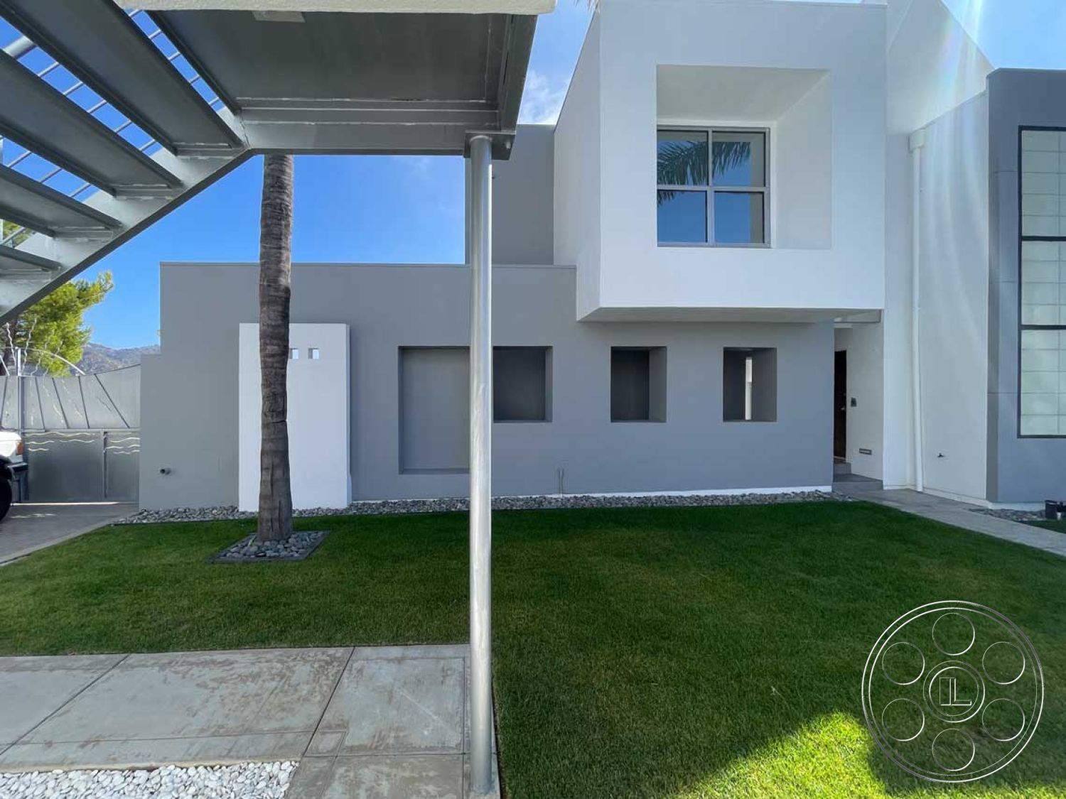 Modern 56 - modern architectural lines, open outdoor space, smooth concrete pathway, geometric window shapes, landscaped grass lawn, minimalist design style, metal stair railing, exposed metal structural elements, exterior concrete façade, white painted stucco walls, planted palm trees, asymmetrical building profile, rectangular window openings, grey stone gravel accents, post-modern exterior detailing