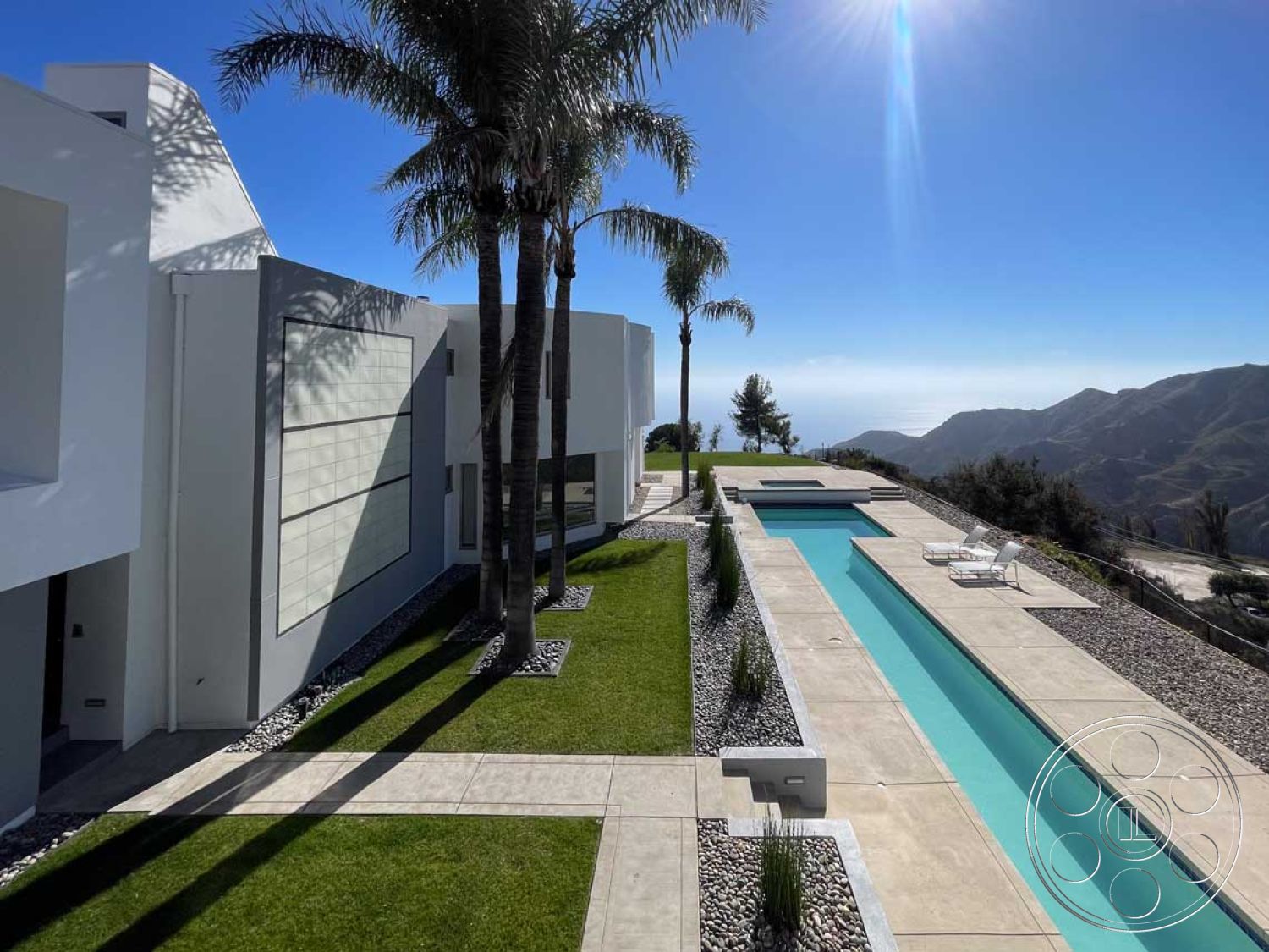 Modern 56 - interior recessed lighting, interior minimalistic design, exterior modern architectural style, interior open floor plan, exterior white stucco walls, exterior glass sliding doors, exterior concrete pool deck, exterior palm trees, interior large windows, exterior mountain view, interior contemporary furnishings, interior modern kitchen, exterior landscaped garden with grass, exterior lap pool, exterior large format tile patio flooring, exterior stone gravel border, interior fresh color palette, interior smooth drywall