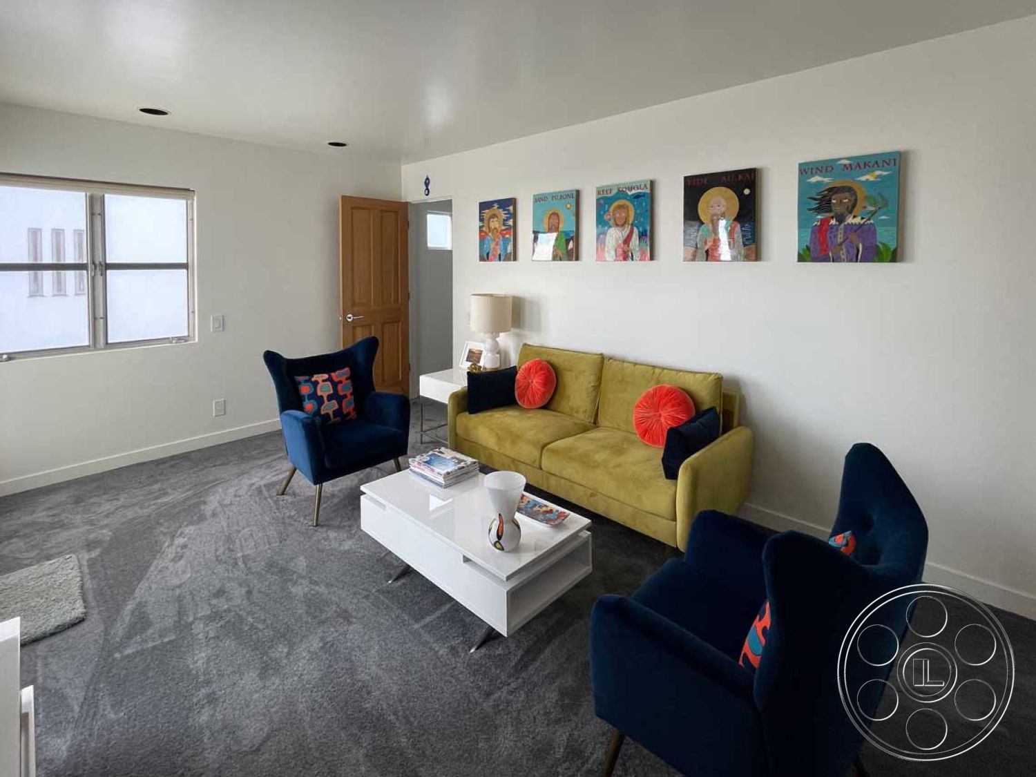 Modern 56 - natural light from windows, flat ceiling with recessed lighting, contemporary art wall decor, modern white painted walls, interior living room with gray carpet flooring, yellow velvet sofa with accent pillows, blue upholstered accent chairs with colorful patterns, glass coffee table with minimalist design, wooden door with traditional design