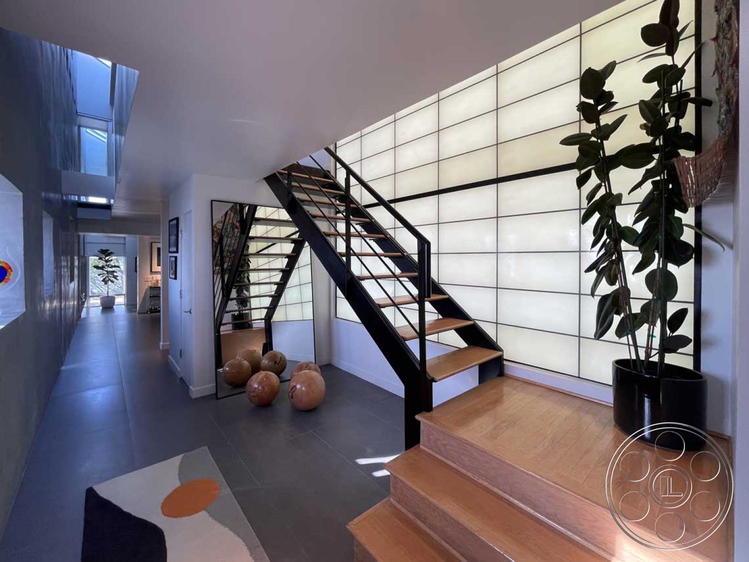 Modern 56 - minimalist design, open floor plan, sliding glass doors, vaulted ceiling, grey tile flooring, stylish area rug, modern art decor, geometric wall patterns, contemporary architectural style, interior hallway, black steel stair railings, decorative ceramic accents, floating wooden steps, textured glass wall, large indoor plant, natural light highlights