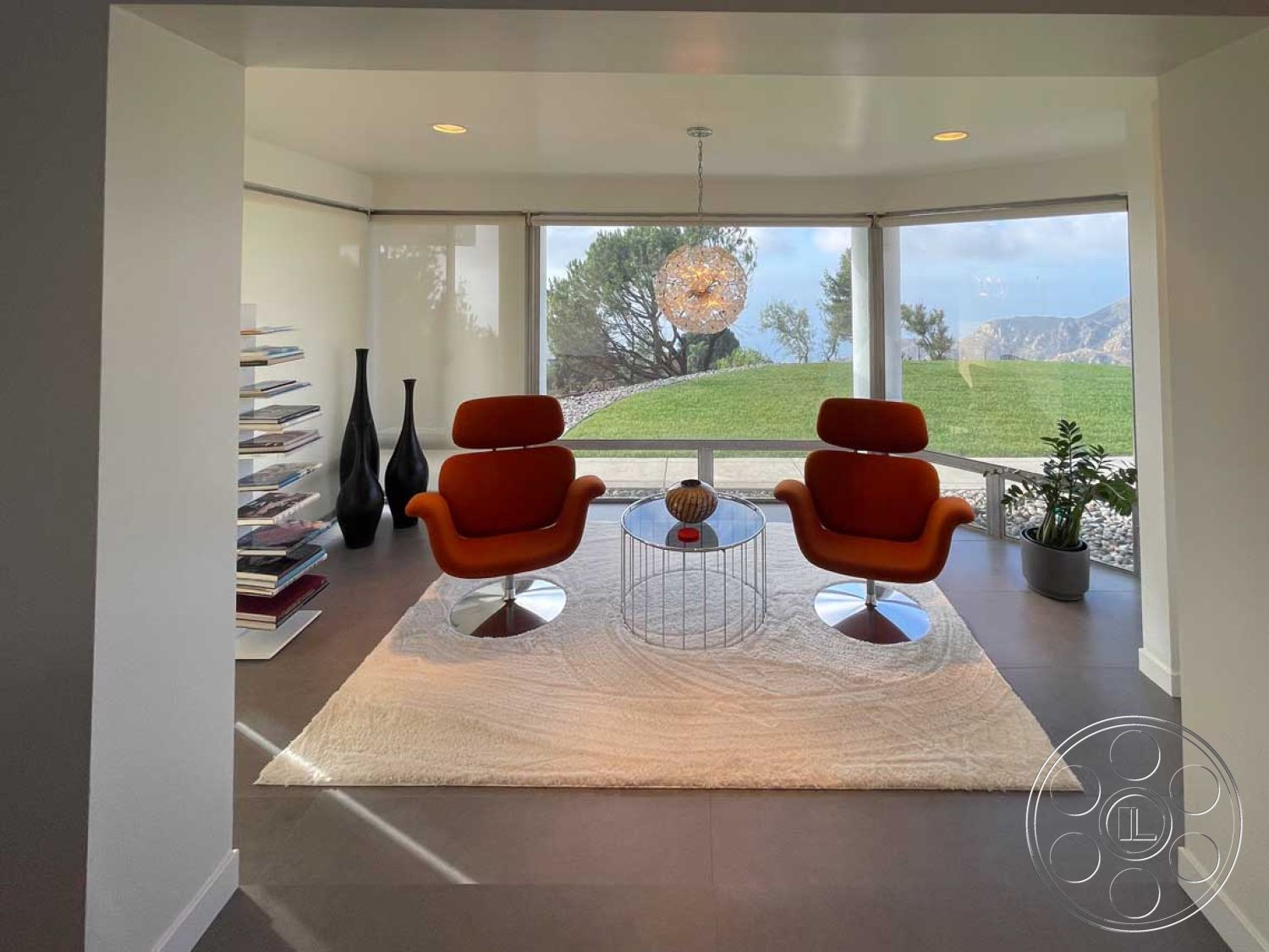 Modern 56 - minimalist decor, textured area rug, open floor plan, glass coffee table, interior space, bright natural lighting, curved wall design, contemporary aesthetic, exposed structural elements, orange accent chairs, modern furniture design, concrete floor tiles, large panoramic windows, lush green landscape view, light fixtures with geometric shapes