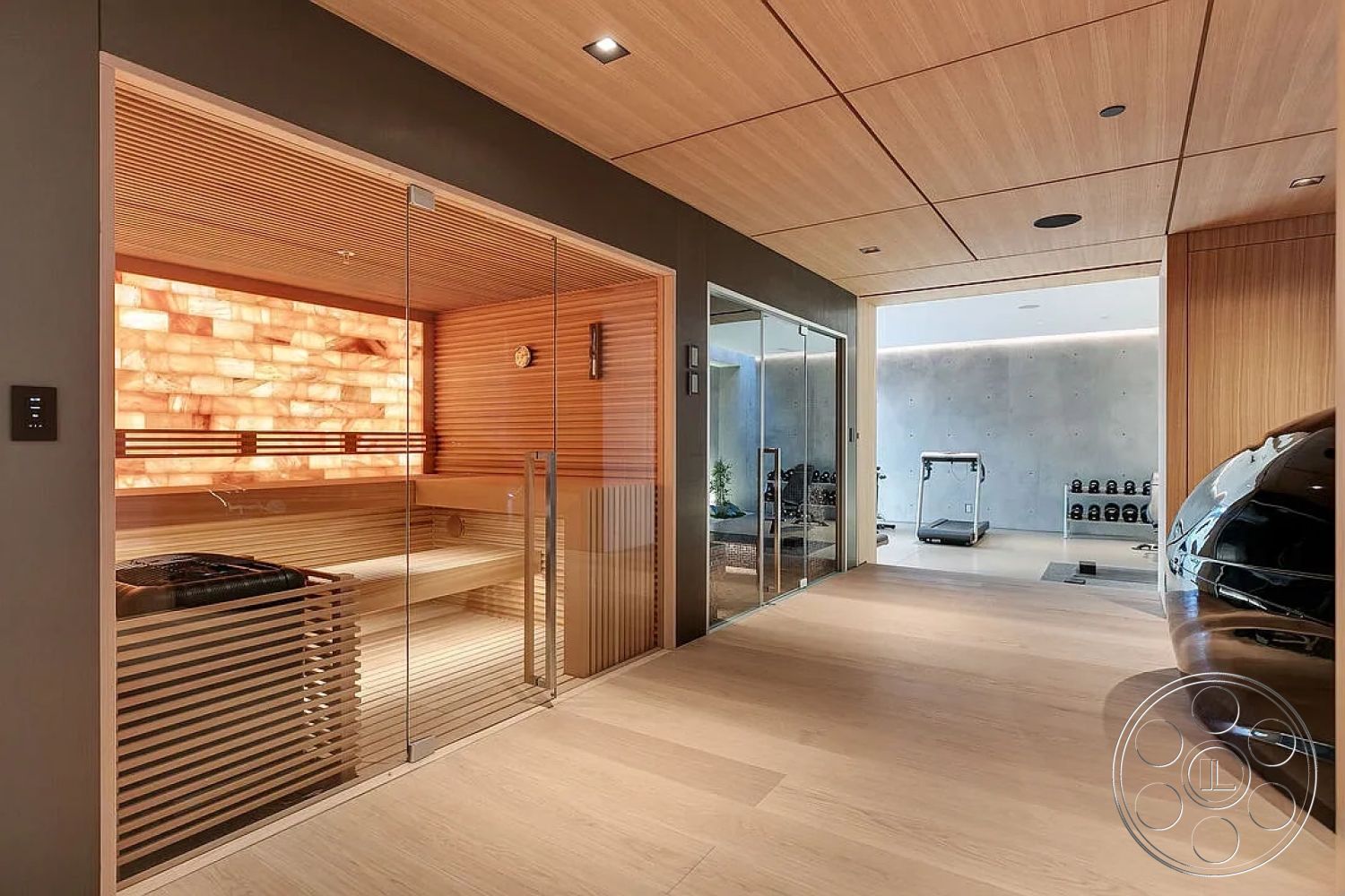Modern 517 - interior sauna with glass enclosure, light wood paneling ceiling with linear grooves, halite stone accent wall, linear wooden bench seating in sauna, textured concrete wall in fitness area, light hardwood flooring in entryway, modern fitness room with gym equipment, clear glass sauna door with sleek handle, minimalist interior design with neutral tones, hidden lighting along wall for ambiance