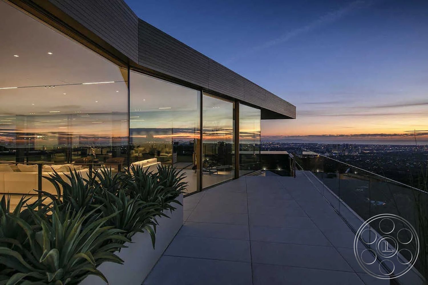 Modern 517 - open floor plan, landscaped greenery, sunset view, seamless indoor-outdoor flow, luxury outdoor space, minimalist architecture, flat roof design, mountain view setting, concrete patio flooring, stone planter boxes, city skyline backdrop, large outdoor terrace, lounge seating area, exterior glass walls, polished concrete surface, modern railing design