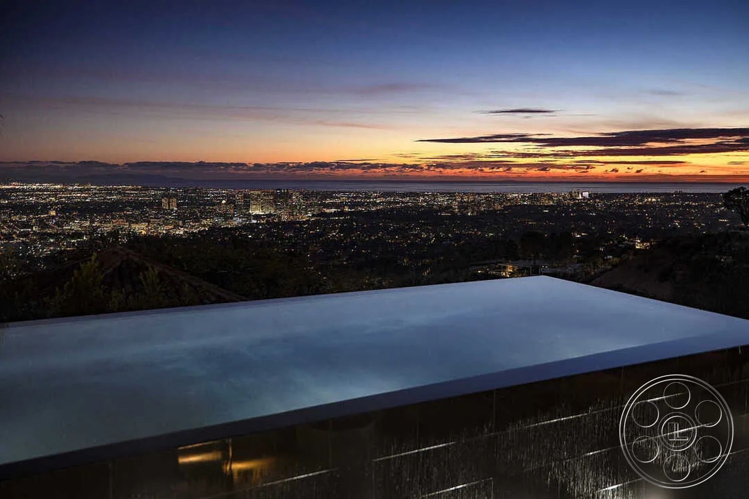 Modern 517 - minimalist design elements, outdoor living space, nighttime ambiance, landscape lighting, luxury home, reflective water surface, view of city skyline, sleek architectural lines, modern home exterior, hardscape materials, infinity pool edge, glass pool border, contemporary pool design, polished concrete patio, mountain hillside setting, open space with panoramic views, transitional outdoor space, sunset view over city, serene outdoor retreat