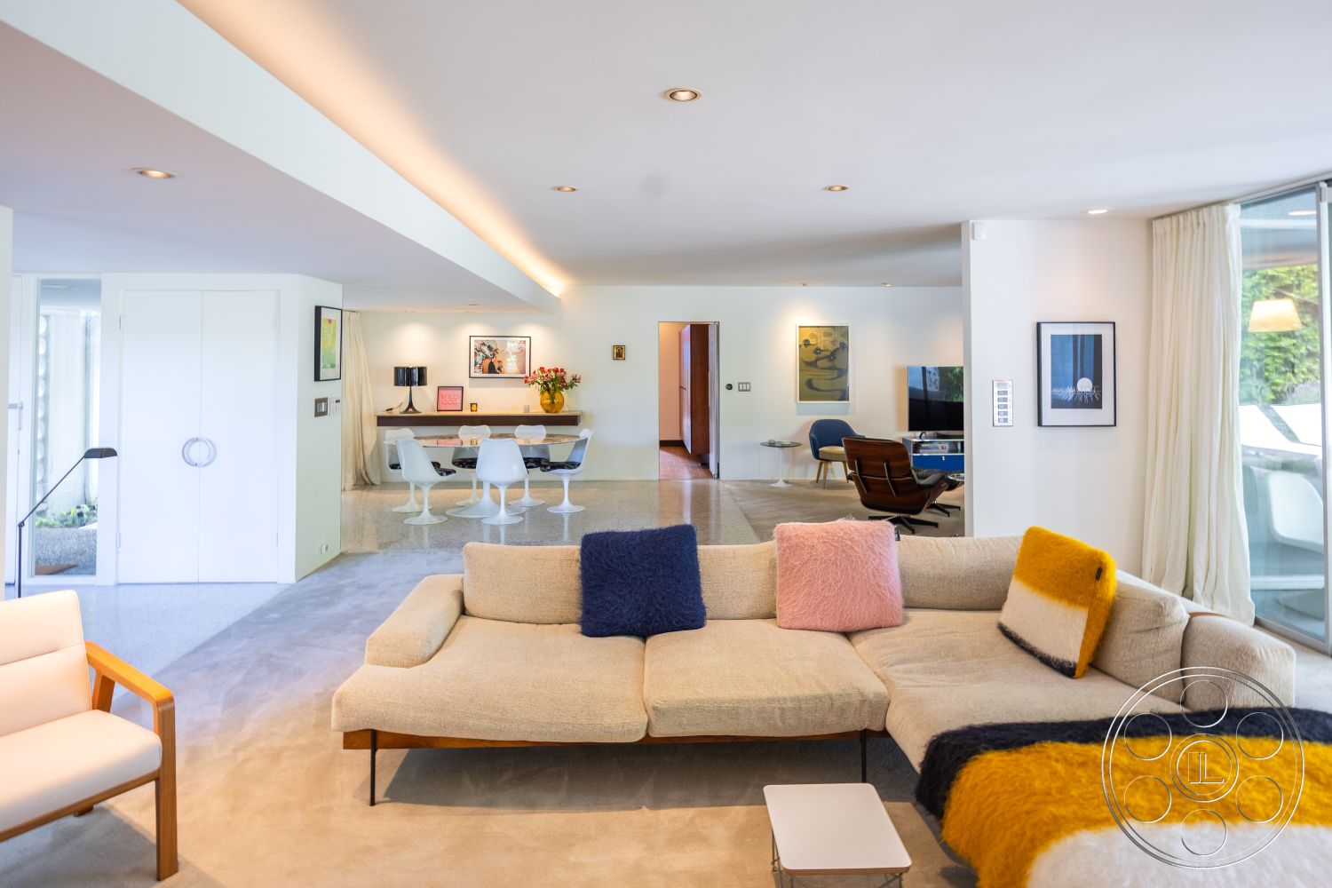 MCM 27 - neutral color palette, textured area rug, polished concrete flooring, open concept layout, glass dining table, curved wall design, large floor-to-ceiling windows, wooden accent furniture, white painted walls, modern sectional sofa, artwork display on walls, contemporary decor elements, stylish indoor plants, interior contemporary living room, design chairs with white shell, exposed recessed lighting, minimalist home office setup, soft drapery for natural light control, architectural details of sleek lines, modern wall art framed