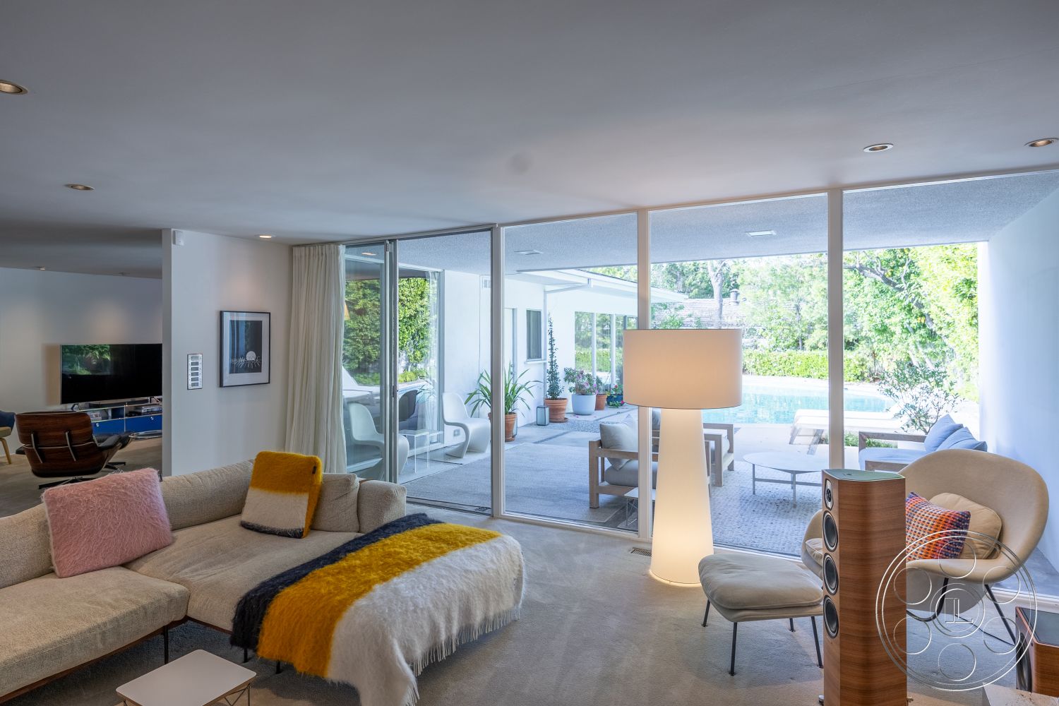 MCM 27 - minimalist design, open floor plan, potted greenery, large sliding glass doors, stone pool deck, concrete patio flooring, mid-century modern architectural style, recessed ceiling lighting, modern sectional sofa, urban garden patio, interior carpet flooring, contemporary floor lamp, exterior pool view, glass wall openings, lightweight furniture arrangement, textile throw blanket