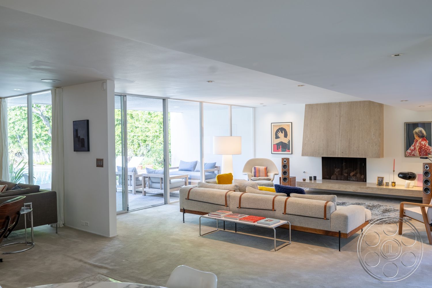 MCM 27 - indoor-outdoor flow, glass sliding doors, urban setting, floor-to-ceiling windows, open concept living space, plush area rug, geometric coffee table, lush greenery outside, patio view, hardwood living room floors, neutral painted walls, modern sectional sofa, contemporary ceiling lights, minimalist art decor, exposed concrete fireplace wall