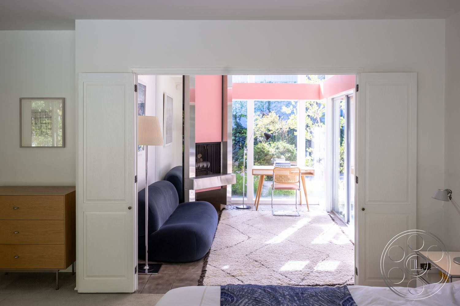 MCM 27 - interior neutral color palette, interior natural light, interior area rug, interior floor-to-ceiling windows, interior white painted walls, interior minimalist design, interior open concept living, interior hardwood bedroom flooring, interior glass partition wall, interior seamless connection to outdoor space, interior wood paneling dresser, interior curved sofa, interior modern desk with wooden legs, interior contemporary lamp, interior modern art wall decor, interior sliding door, interior bright color accents, interior organized workspace