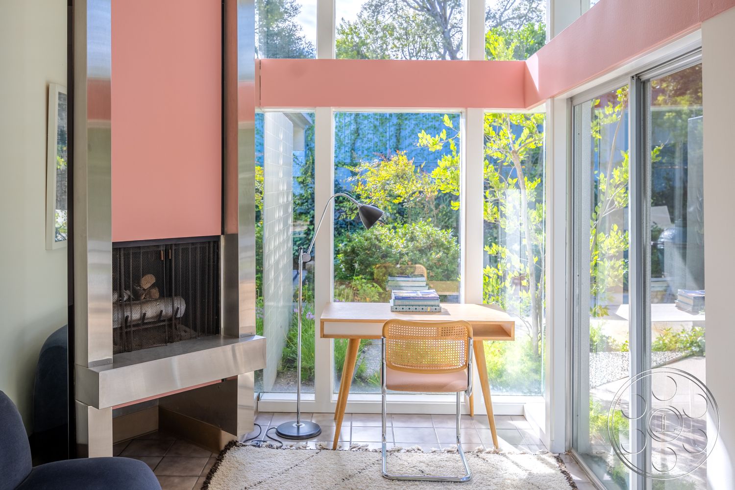 MCM 27 - interior contemporary design, interior minimalist decor, interior decorative area rug, interior floor-to-ceiling windows, interior glass walls, interior open living space, interior potted plants, interior stainless steel fireplace surround, interior pink accent wall, interior natural wood desk, interior hardwood floor tiles, interior modern desk lamp, interior indoor-outdoor connection, interior upholstered chair, interior bright natural light