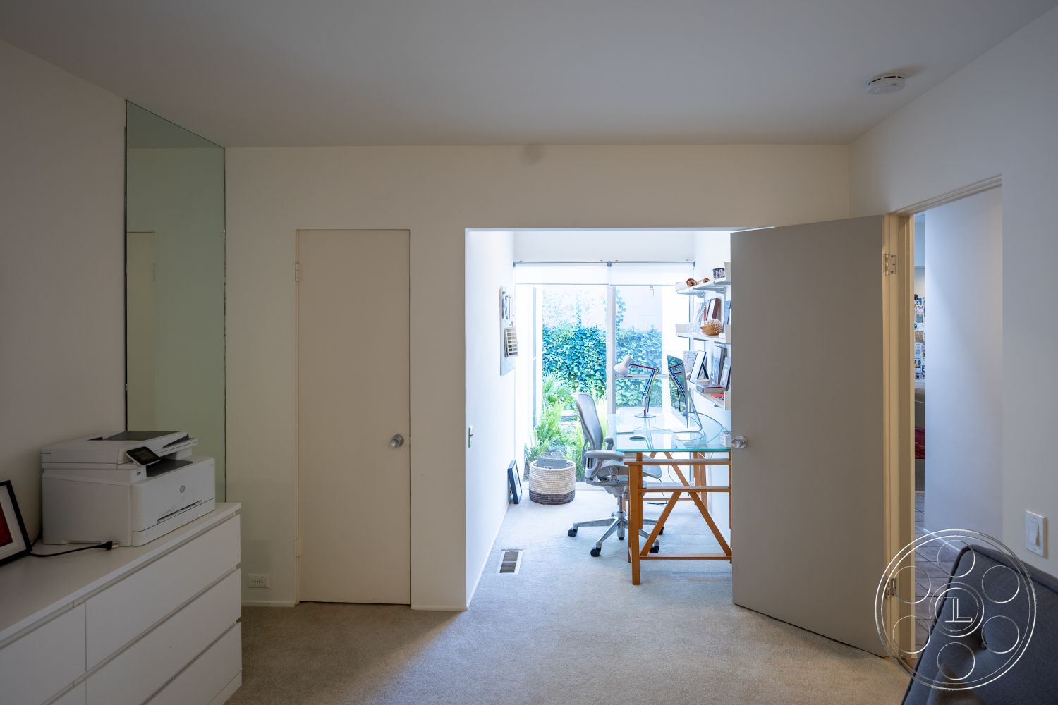 MCM 27 - neutral color palette, natural light from large windows, contemporary light fixtures, organized workspace, built-in shelving unit, modern office space, smooth drywall finishes, carpet bedroom flooring, glass office desk, open concept entryway, walls with white paint, minimalist style doors, soft textured rug