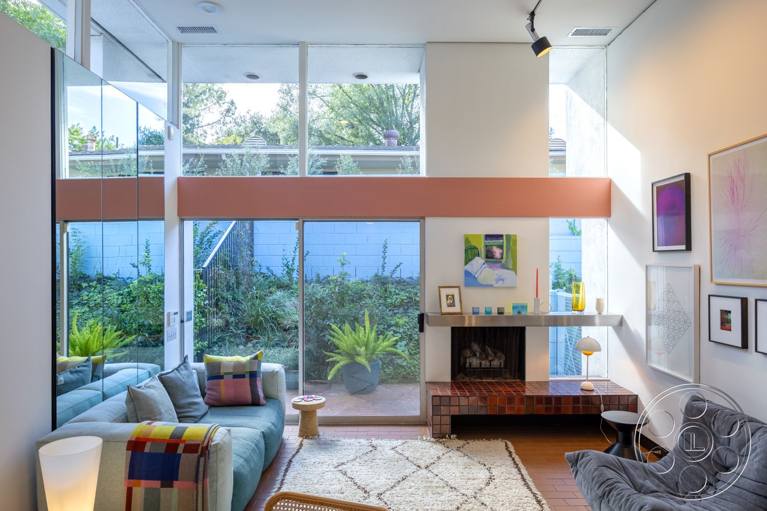 MCM 27 - neutral color palette, textured area rug, open floor plan, glass walls, floor-to-ceiling windows, wooden ceiling beams, orange accent wall, stylish coffee table, indoor plant decor, simple geometric patterns, interior living room, exposed brick fireplace surround, soft fabric sofa, natural light-filled space, built-in shelving units, clean lines architecture, contemporary art pieces, concrete floor tiles, modern minimalist furniture, multicolored throw pillow accents