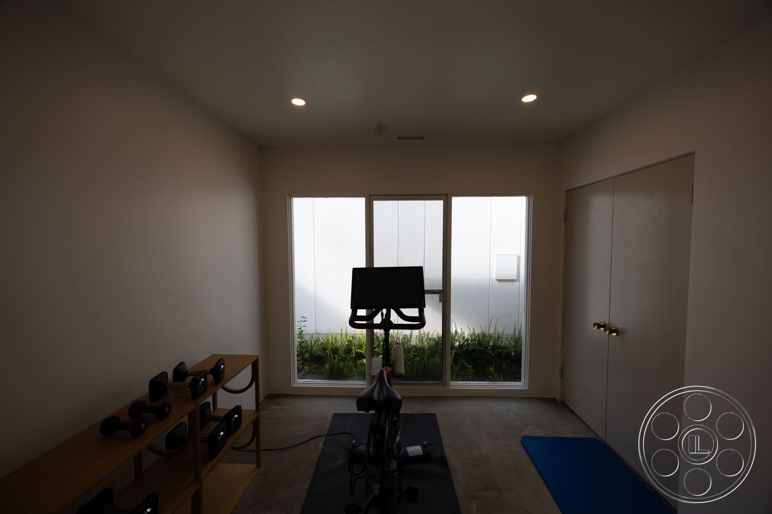 MCM 27 - neutral color palette, contemporary design, open layout, minimalist style, carpet flooring, white painted walls, interior fitness room, glass window wall, natural light source, wooden exercise equipment shelf, dimensional LED ceiling lights