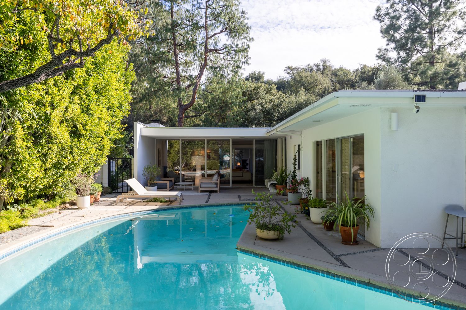 MCM 27 - exterior, white stucco walls, sliding glass doors, rectangular swimming pool, floor-to-ceiling windows, lush landscaping, modern lounge chairs, concrete patio flooring, wood beam ceiling, urban retreat setting, private backyard oasis, natural stone pool border, container plants