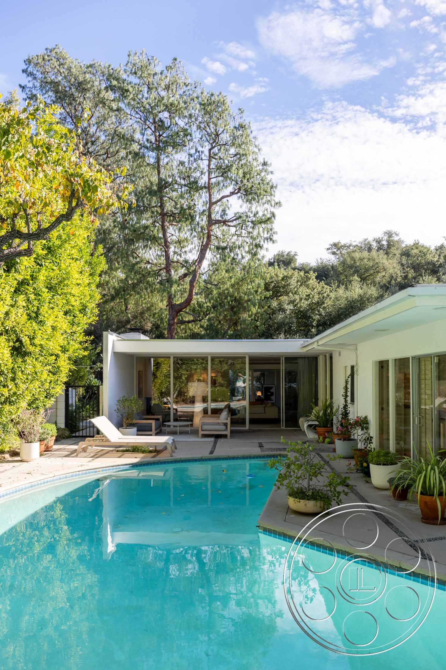 MCM 27 - exterior, sliding glass doors, exposed concrete walls, rectangular swimming pool, surrounding trees, floor-to-ceiling windows, stone pathway, urban oasis, concrete pool deck, minimalist architecture, wooden privacy fence, sunny outdoor setting, flat roof design, landscaped garden area, contemporary outdoor living space, planter pots with greenery, patio lounging area, natural wood lounge chairs, abstract modern home design