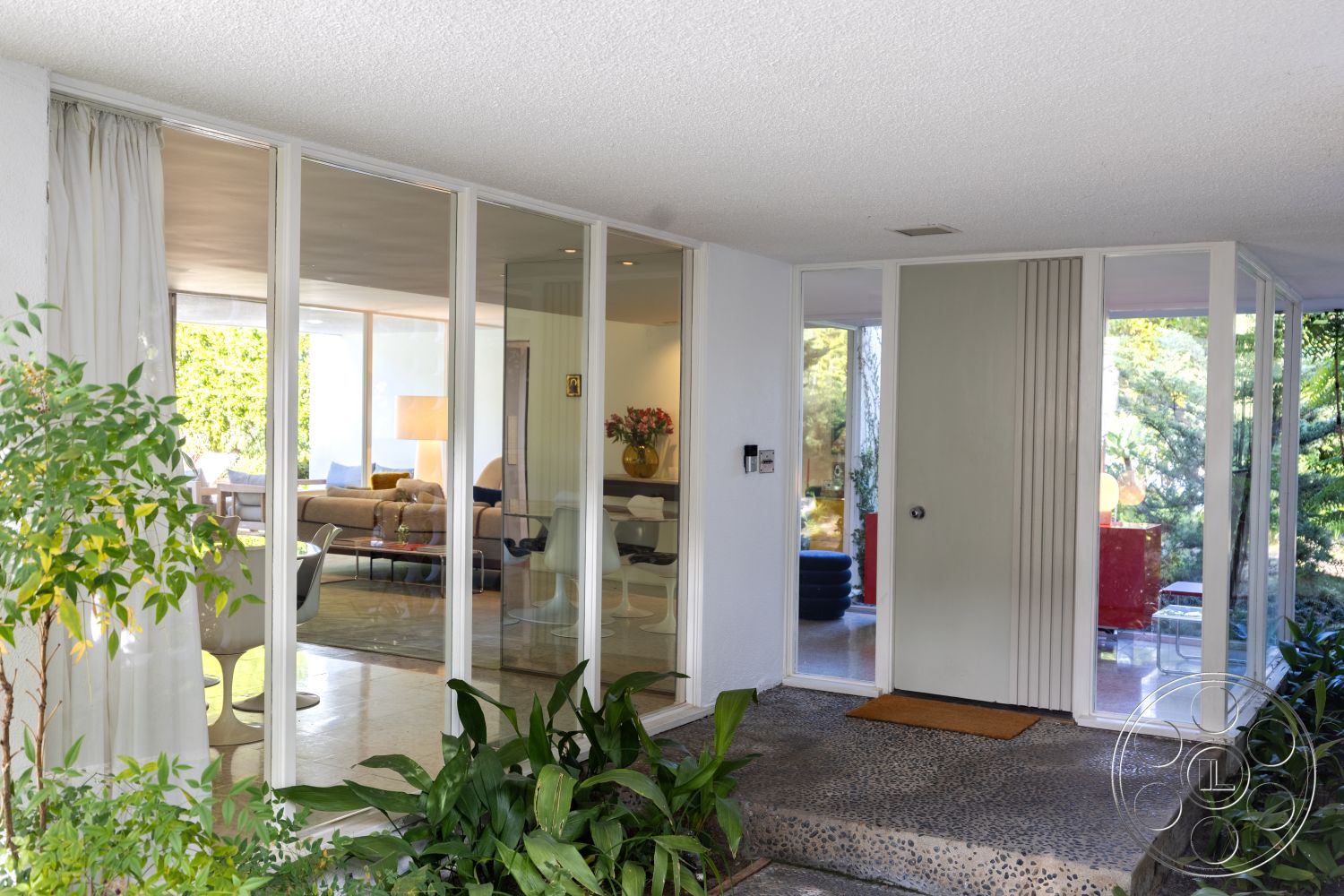 MCM 27 - exterior, sliding glass doors, Mid-Century Modern architecture, landscape greenery, open floor plan layout, integrated indoor-outdoor living, smooth white ceiling, monochrome color scheme, modern front door design, glass entryway walls, pebble stone walkway, contemporary patio view, natural light-filled surroundings