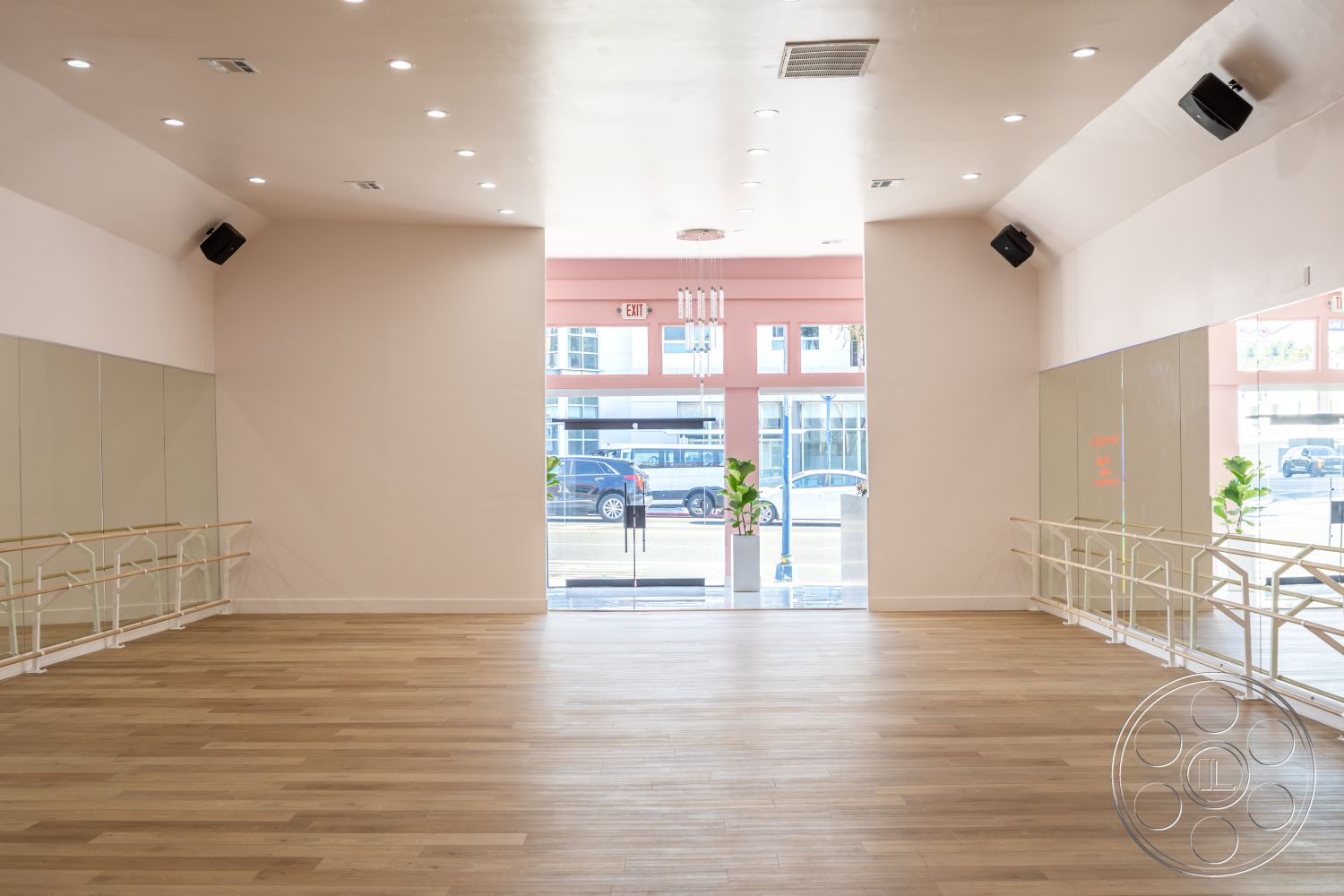 Gym 37 - natural light, modern decor, open layout, exposed beam ceiling, plant decoration, interior hardwood flooring, white painted walls, LED recessed lighting, mirrored wall treatment, bright, airy atmosphere, dance studio space, ballet bar installation, large glass entrance