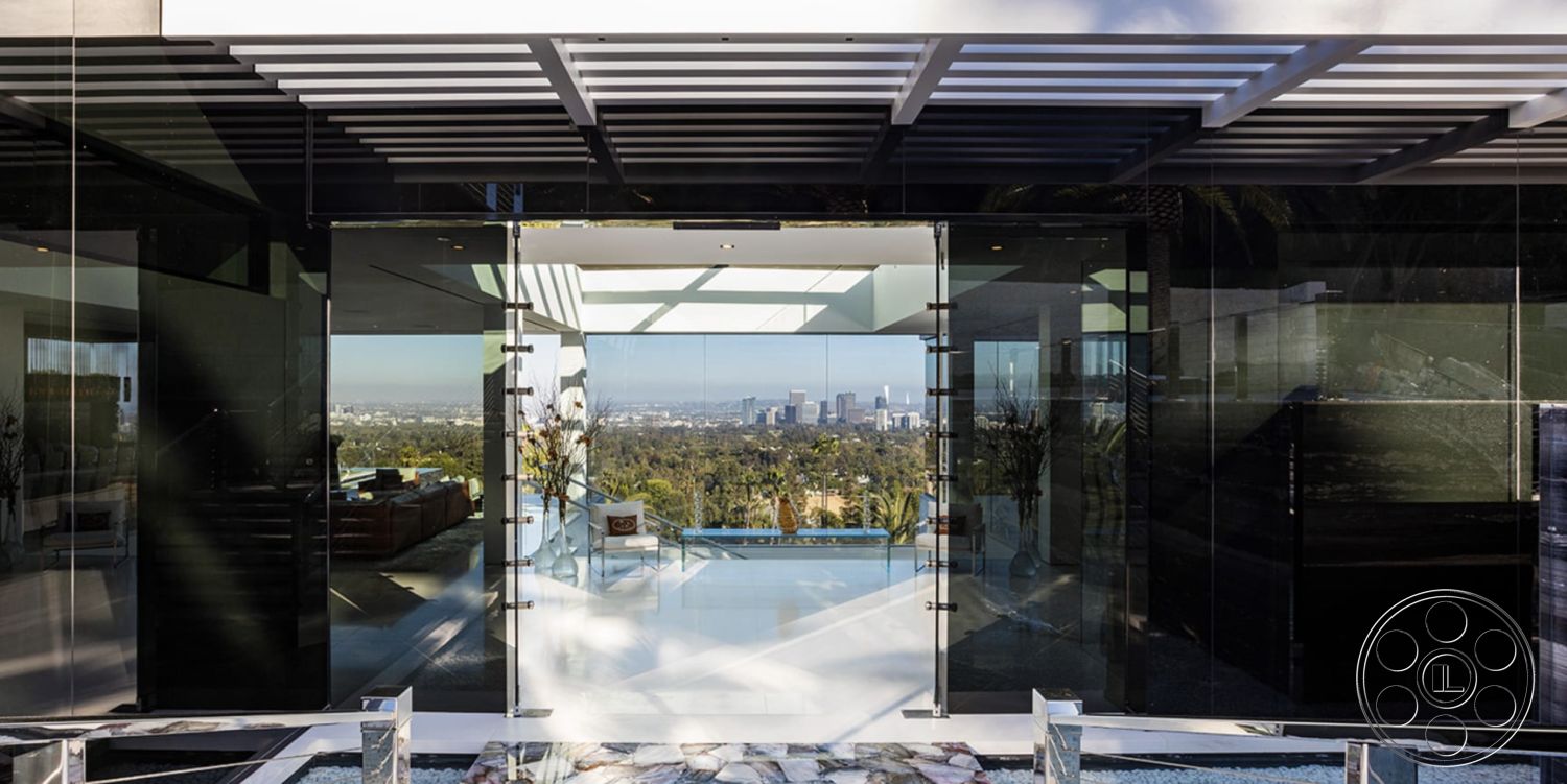 Modern 518 - polished concrete flooring, sliding glass doors, floor-to-ceiling windows, natural light-filled space, interior open floor plan, minimalist architectural design, concrete patio floor, exterior glass entrance doors, city skyline view from patio, contemporary outdoor living area, modern pergola structure, luxury residential architecture, urban setting with panoramic views, black framing details, landscape stone detail, clear glass walls, sleek neutral color palette, architectural overhang, smooth white wall surfaces, outer terraced landscaping