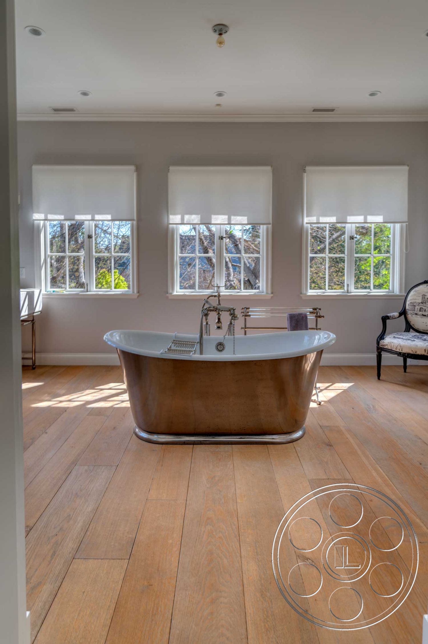 The French Chateau - minimalist decor, open concept layout, casual seating area, natural light from large windows, soft window treatments, textured ceiling details, interior bathroom space, modern bathroom design, white painted walls, wide plank hardwood flooring, freestanding copper bathtub, luxury spa-like ambiance, elegant transitional style, exterior view of trees