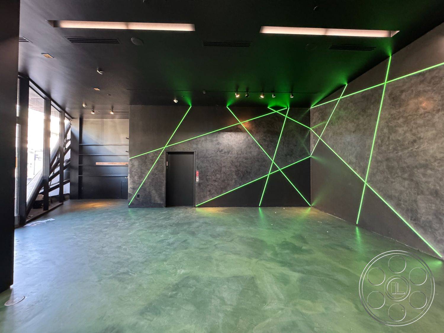 Sunset Studio - minimalist decor, concrete floor, interior space, industrial design, floor-to-ceiling windows, commercial space, modern architectural style, angular lines, black painted walls, open floor layout, creative studio environment, exposed structural beams, polished concrete surface, green LED accent lighting