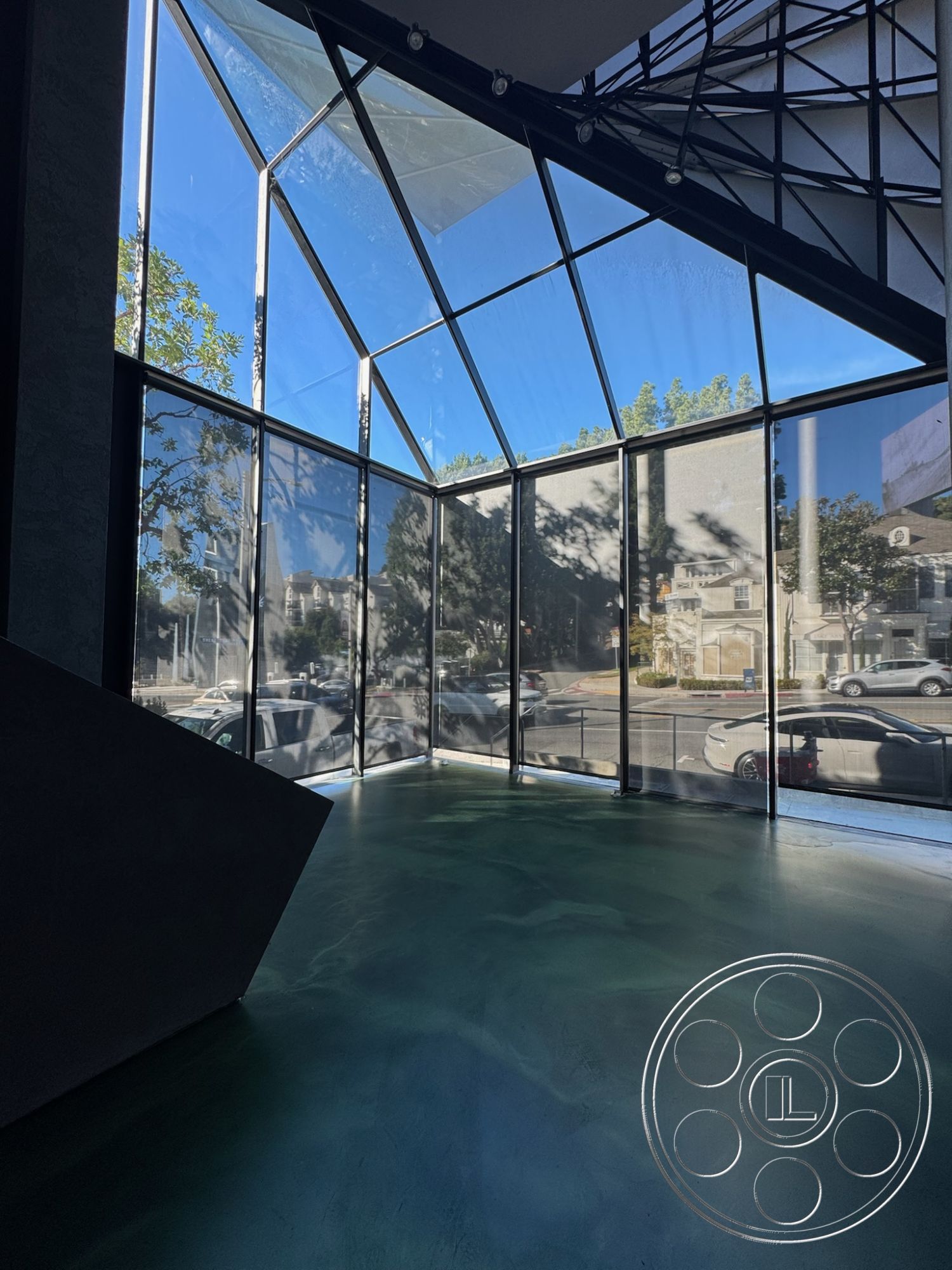 Sunset Studio - open floor plan, polished concrete floors, urban setting, modern architectural style, large floor-to-ceiling windows, contemporary living space, exposed steel framework, interior glass curtain wall, geometric shape design, sleek minimalist aesthetics