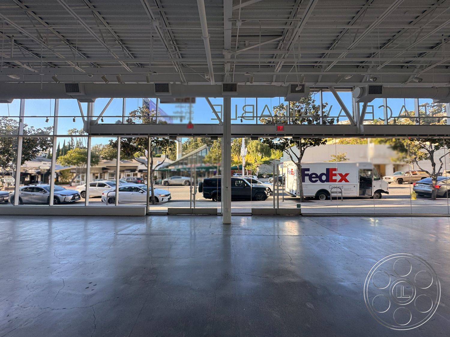 Sunset Storefront - polished concrete floor, vaulted ceiling with exposed beams, minimalist architectural style, urban commercial setting, large glass storefront windows, exposed metal framing interior, open floor plan retail space, bright interior with natural light, view of city street, accessible entrance space