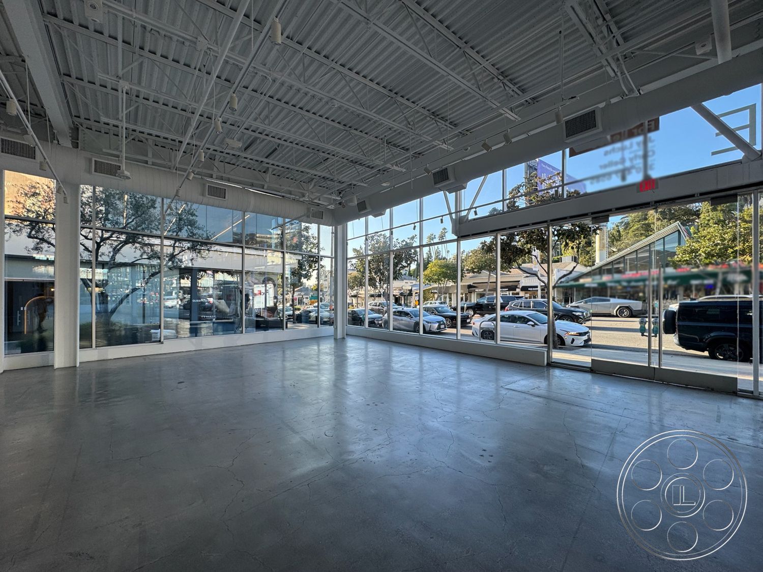 Sunset Storefront - high ceilings, polished concrete flooring, contemporary architectural style, modern minimalist design, open floor plan layout, floor-to-ceiling glass windows, natural light abundance, exposed metal ceiling beams, urban street view, interior industrial space, commercial showroom, flexible space for retail or office