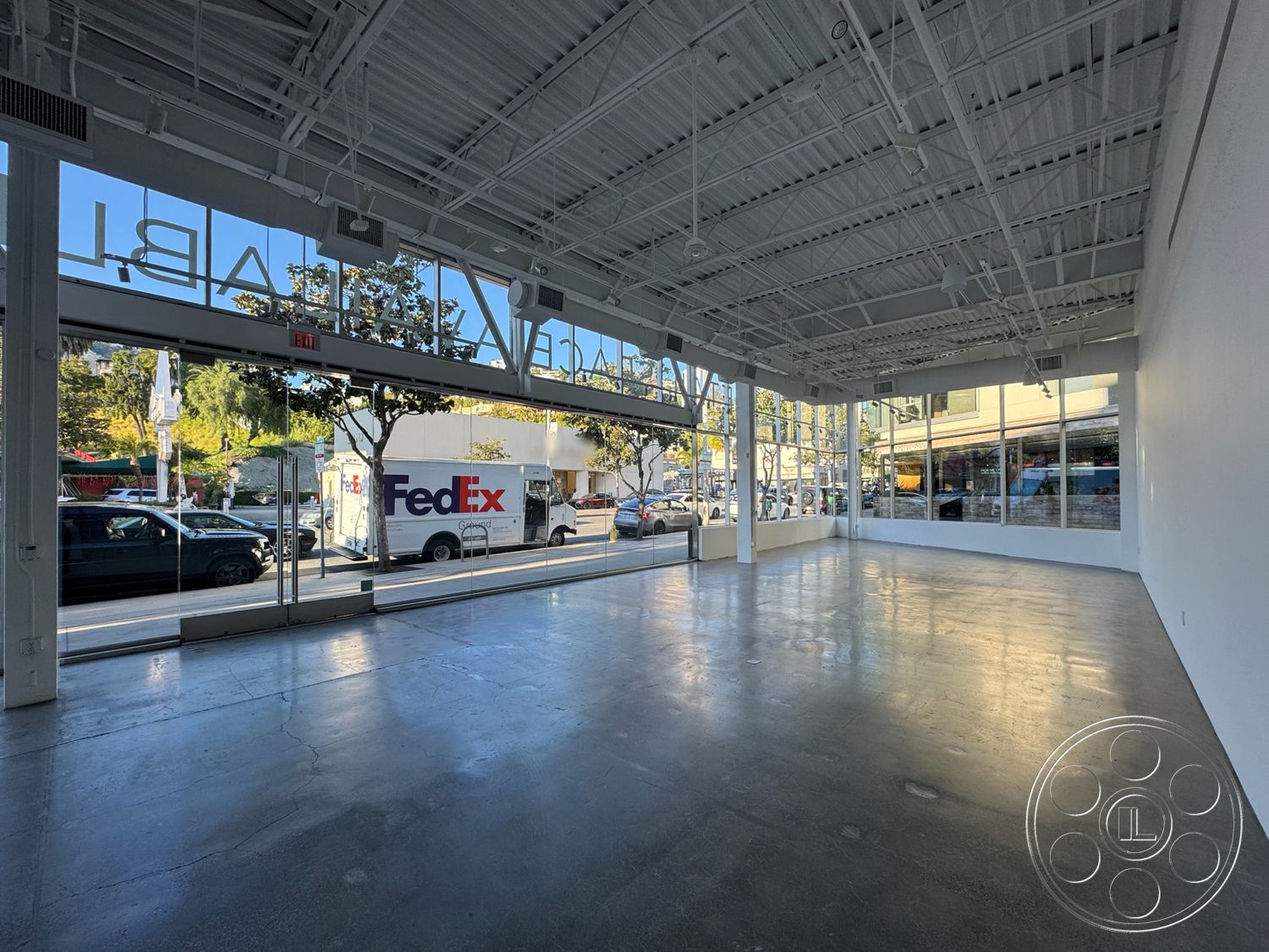 Sunset Storefront - minimalist design, open floor plan, polished concrete flooring, modern aesthetic, bright natural lighting, large floor-to-ceiling windows, white painted walls, industrial style architecture, exposed metal ceiling beams, urban setting view, commercial space layout, exterior glass storefront, street-facing entrance, high ceiling height, interior unfinished concrete